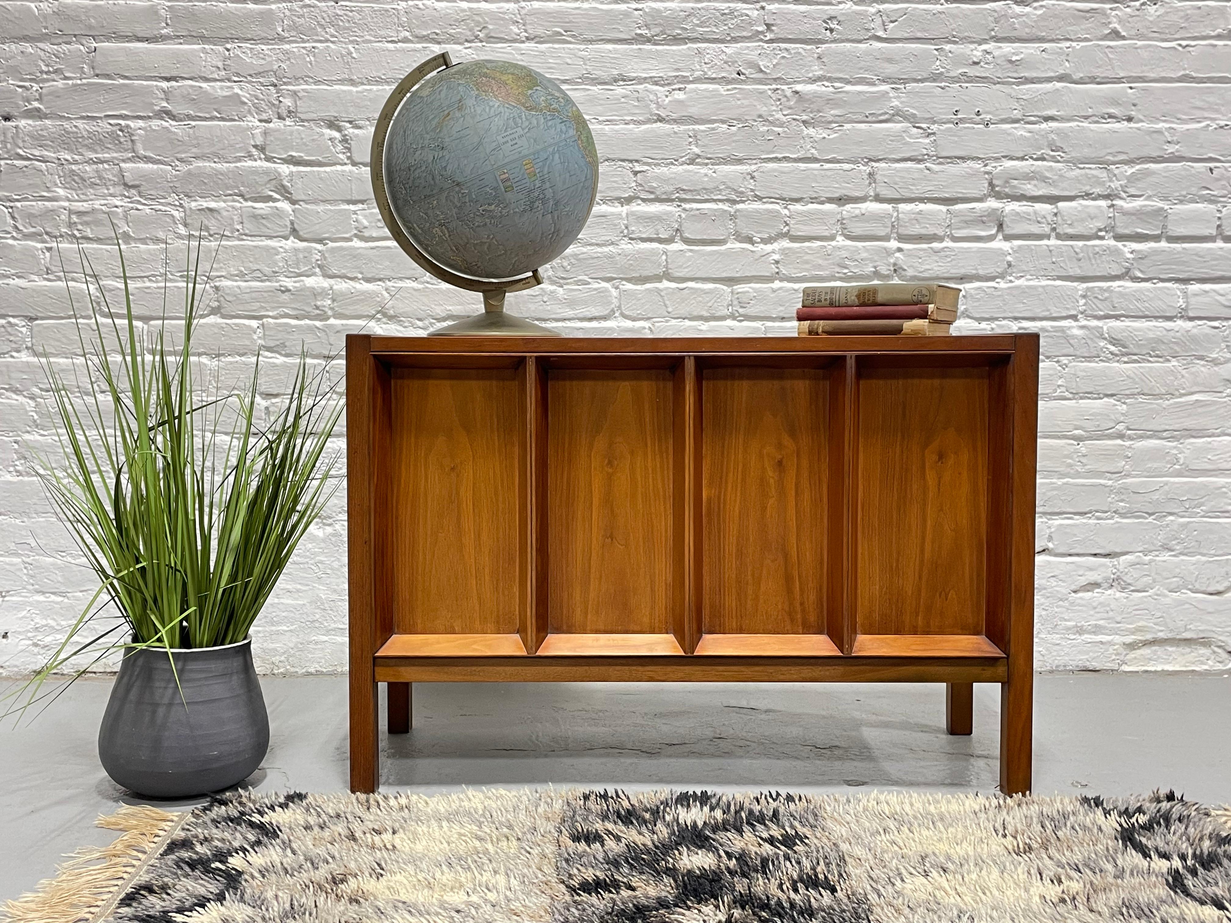 Mid Century Modern Walnut liquor / bar cabinet with incredible sculpted facade, c. 1960's. This unique piece offers a drop down door that opens to a liquor cabinet with space for shot glasses and your liquors. The drop down door is perfect for