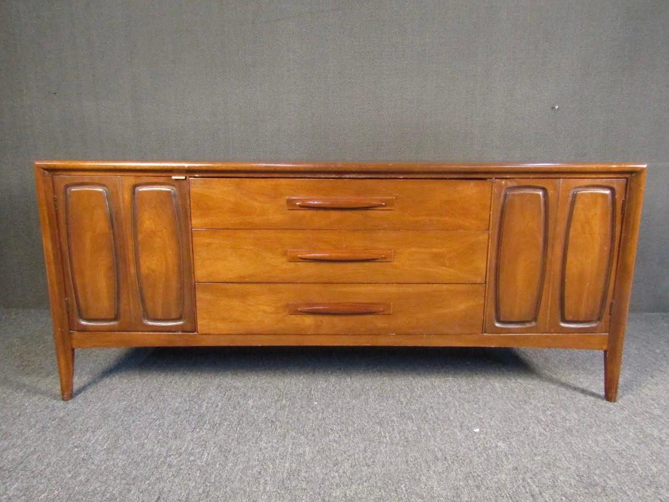 Gorgeous Mid-Century Modern server in rich walnut. Three large drawers with sculpted handles pull out, along with swinging doors on each side revealing spacious compartments. Please confirm item location with seller (NY/NJ).