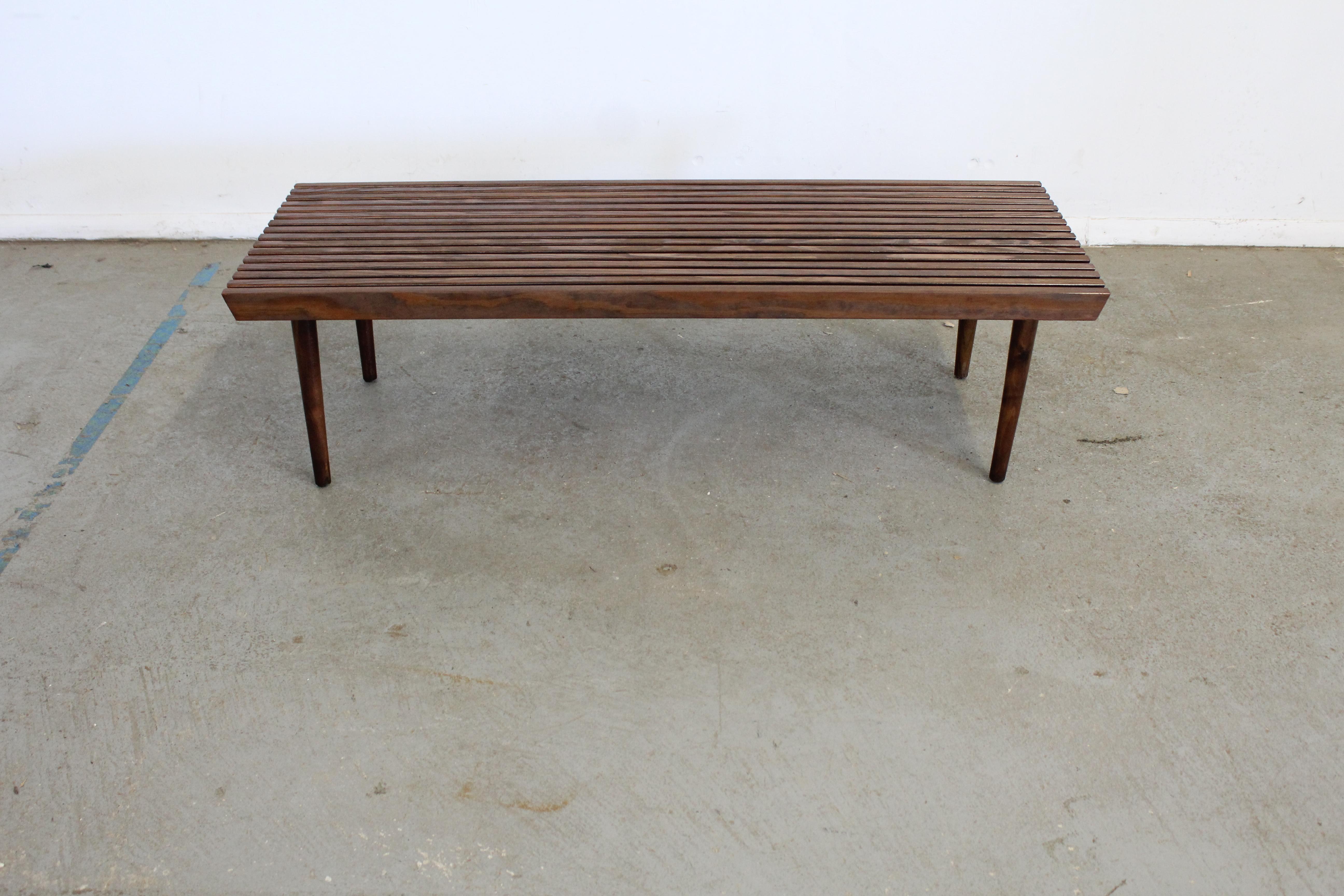 Mid-Century Modern walnut slat bench end/coffee table

Offered is a vintage Mid-Century Modern walnut side table. Has been refinished and is in good condition with minor surface wear/chips. It is structurally sound and stable. It is not signed.