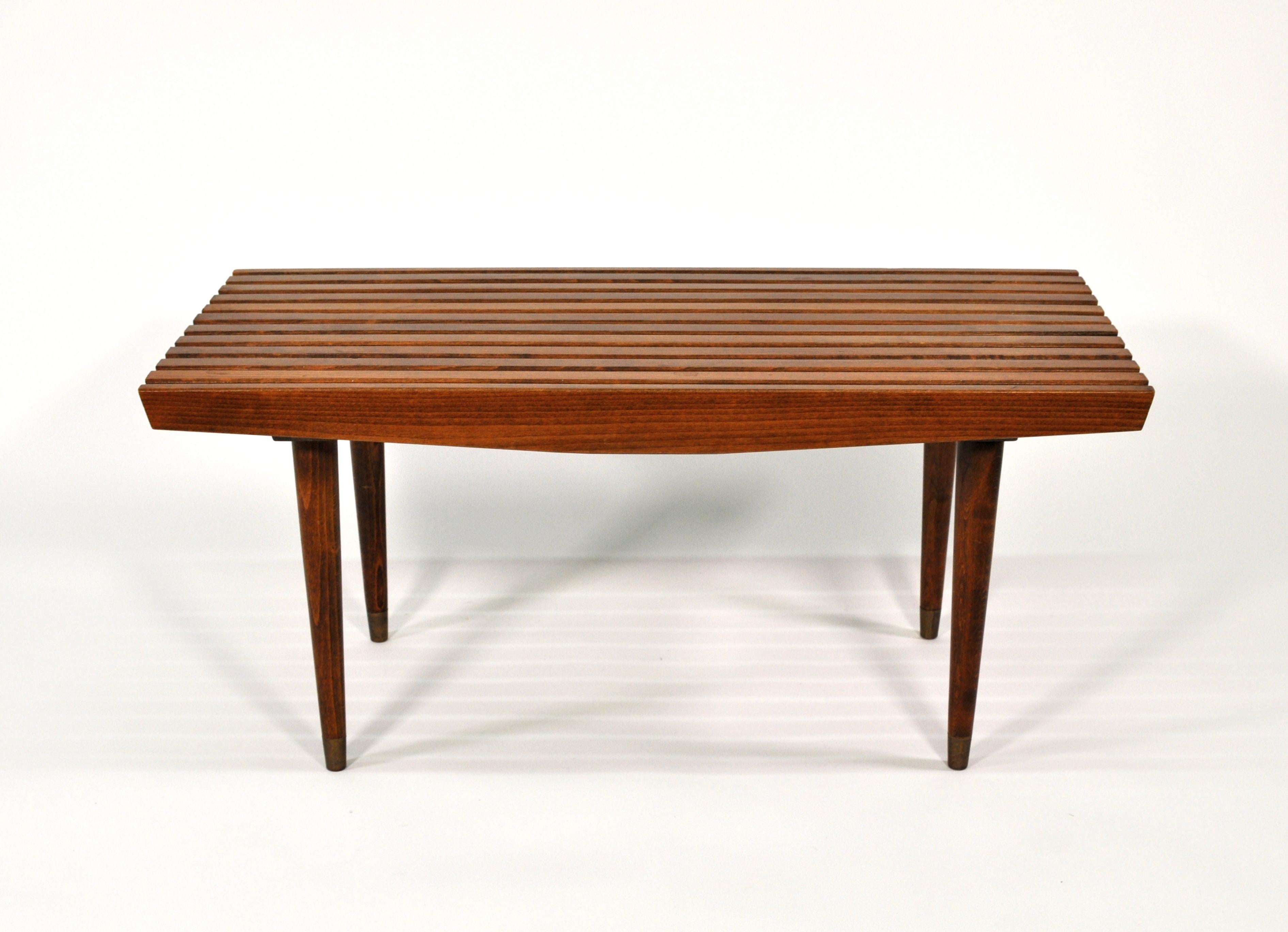 A midcentury slatted wood bench or coffee table, dating from the 1960s. The vintage bench features long and slender tapered legs. It can be used virtually anywhere: as a cocktail or sofa table, at the foot of a bed, under a window, in an entrance