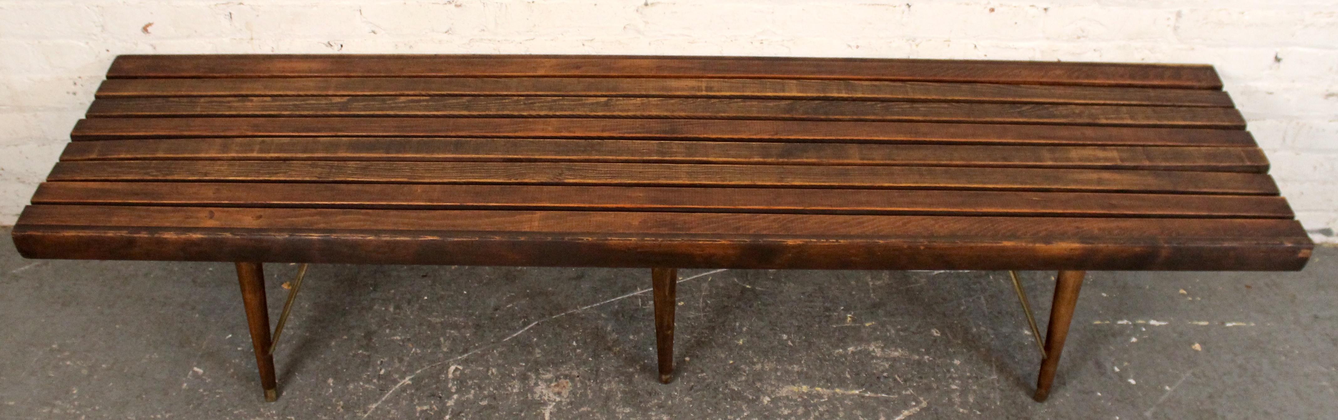 Un banc à lattes en noyer intemporel et moderne du milieu du siècle, au design épuré et minimaliste, avec une construction en noyer massif et des lattes joliment espacées. Le ton chaud et la fabrication raffinée soulignent son attrait polyvalent,