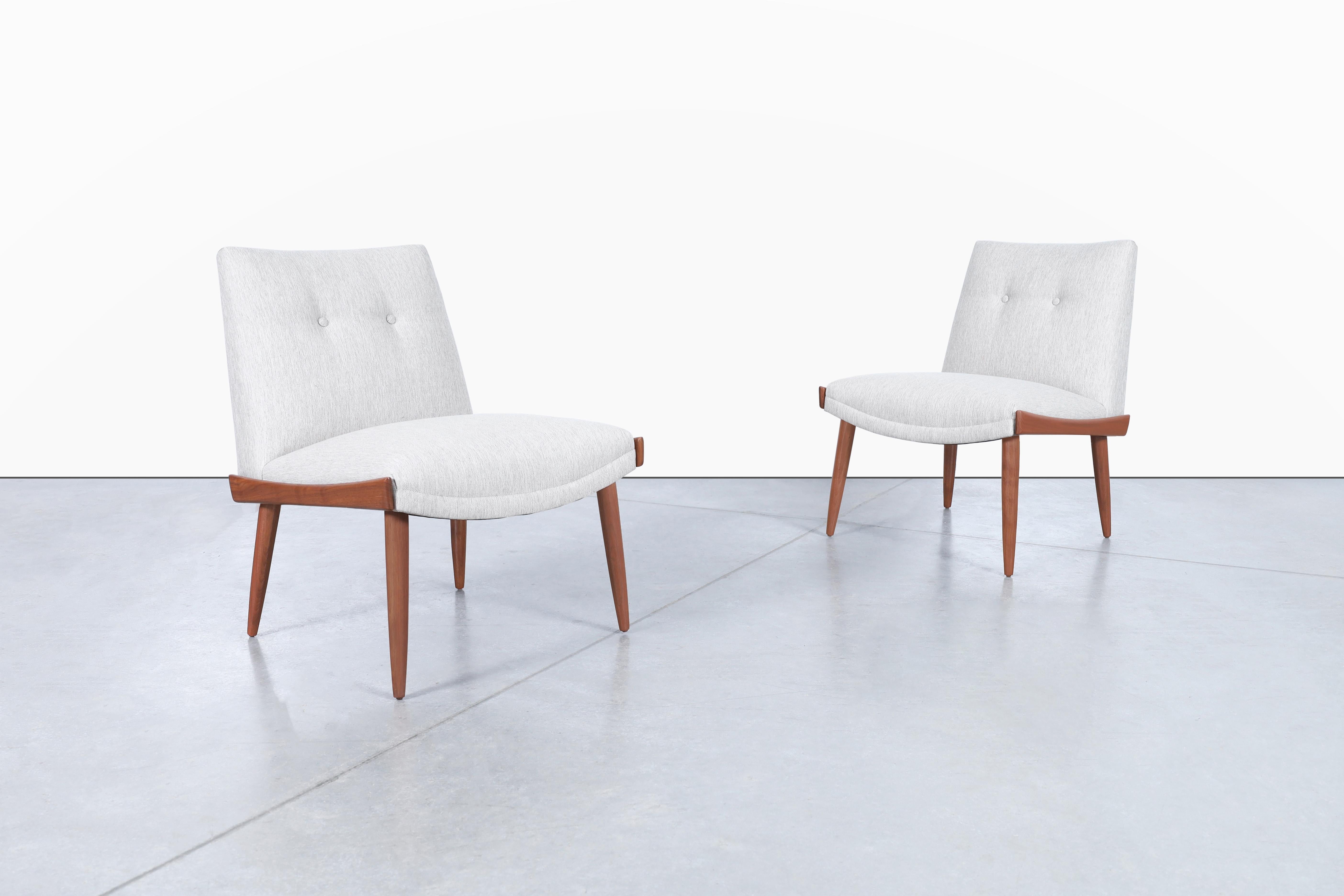 Mid-century modern walnut slipper chairs designed by Kroehler in the United States, circa 1960s. These chairs are not just a pair of chairs, but a statement piece that exudes elegance and charm. The sculptural walnut sides and tapered solid walnut
