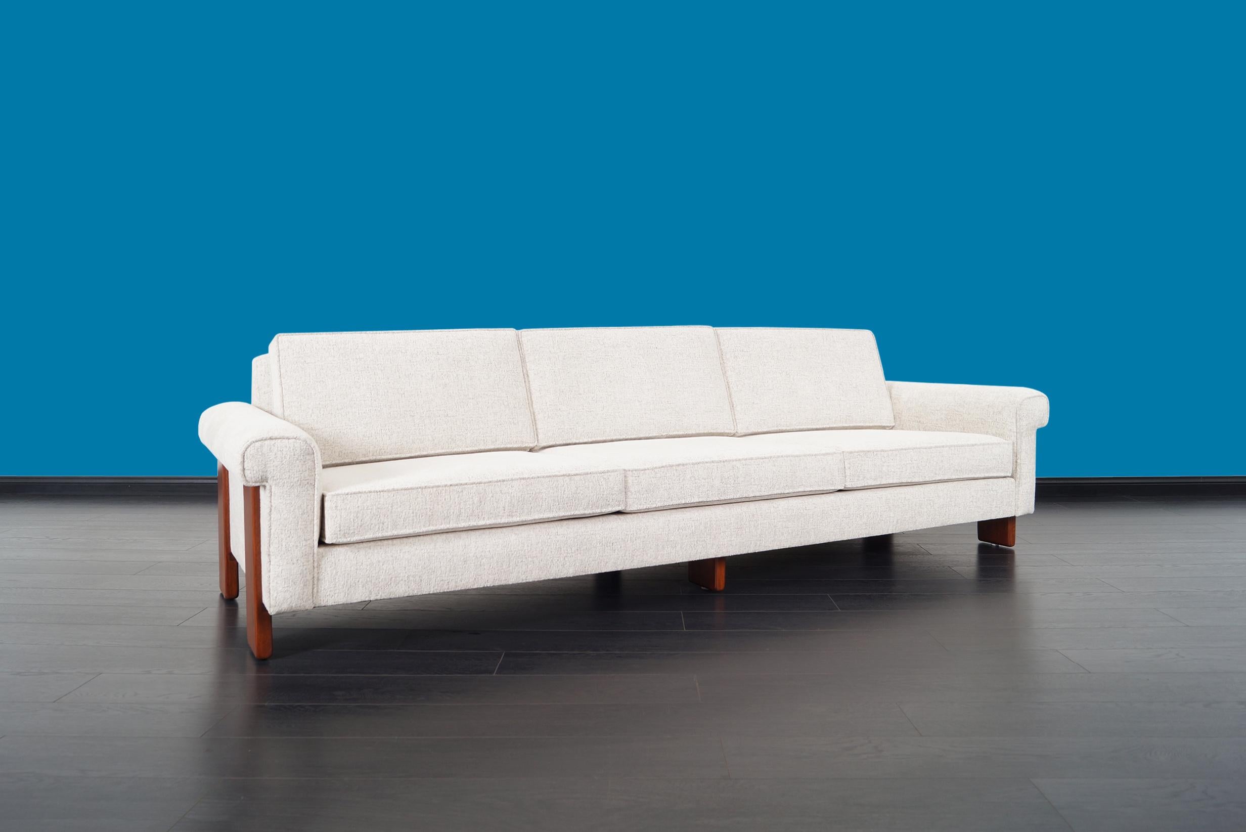 An elegant Mid-Century Modern sofa. Features solid walnut legs and newly reupholstered.