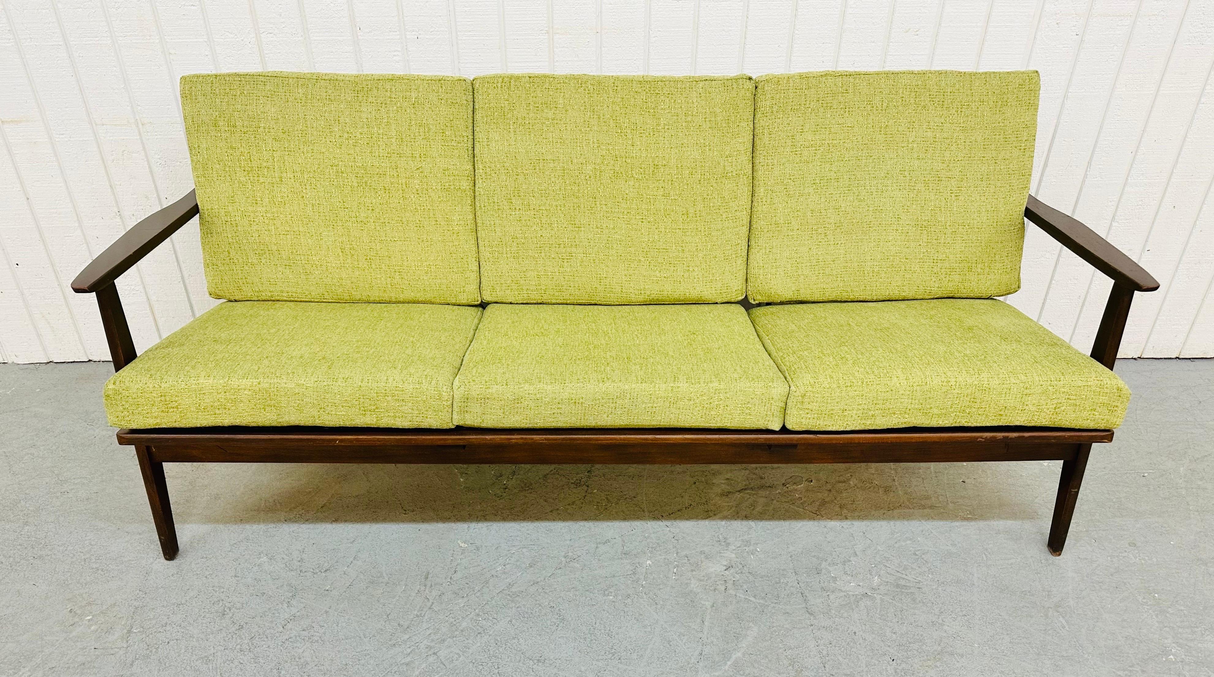 This listing is for a Mid-Century Modern walnut sofa. Featuring a walnut frame, new nylon straps, six newly upholstered avocado green cushions, and a folding backrest for easy transport.