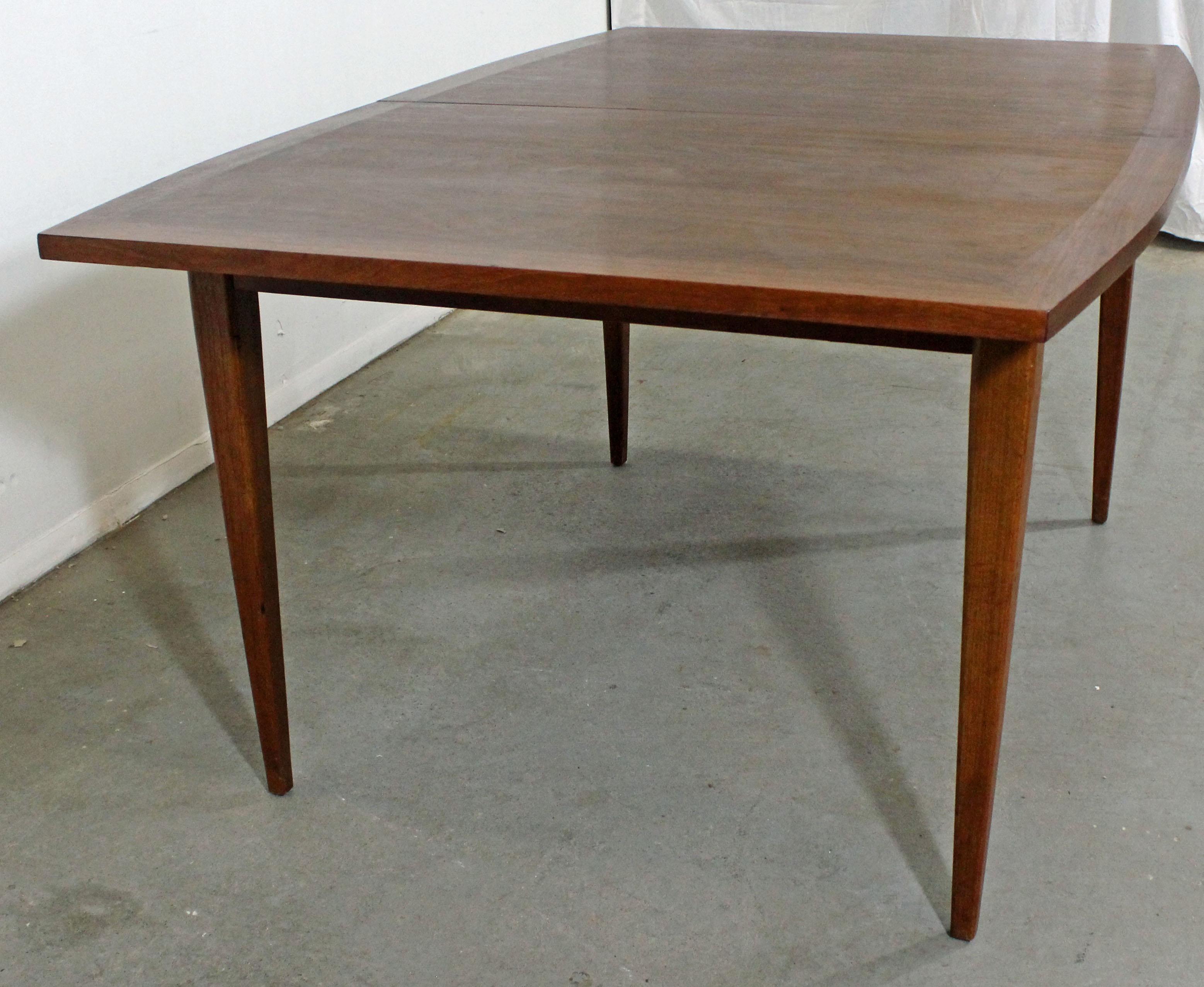 Offered is a Mid-Century Modern walnut dining table with a surfboard-top and three extension boards. It is in good condition, showing some surface/age wear (veneer chips, scratches-- see photos). It is not signed. Check out our other listings for