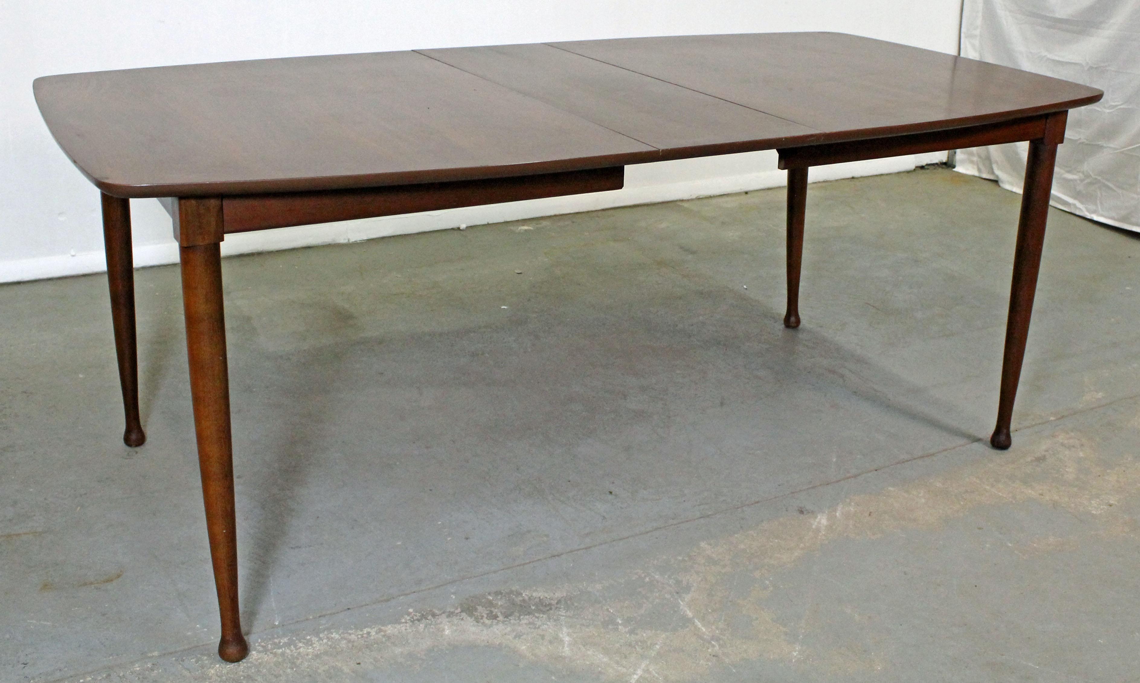 Offered is a Mid-Century Modern walnut dining table with a surfboard-top. Includes one extension board. It is in very good condition, showing minor surface/age wear. It is not signed.

Dimensions: 
62