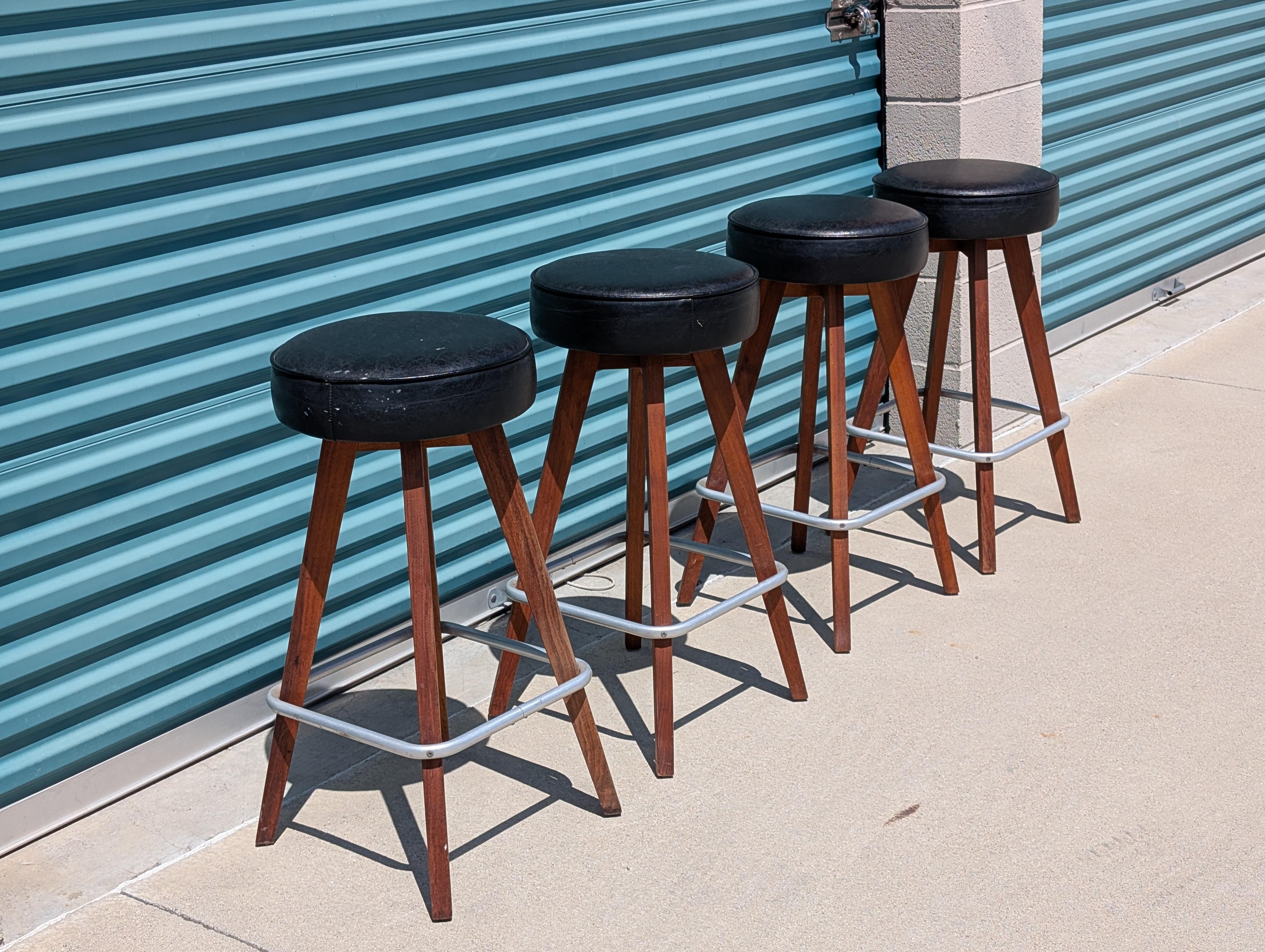 Aggiungi una raffinatezza senza tempo al tuo spazio con questa coppia di sgabelli da bar vintage Mid-Century Modern degli anni '60. Realizzati con gambe in noce massiccio e sormontati da eleganti sedili girevoli in vinile nero, questi sgabelli