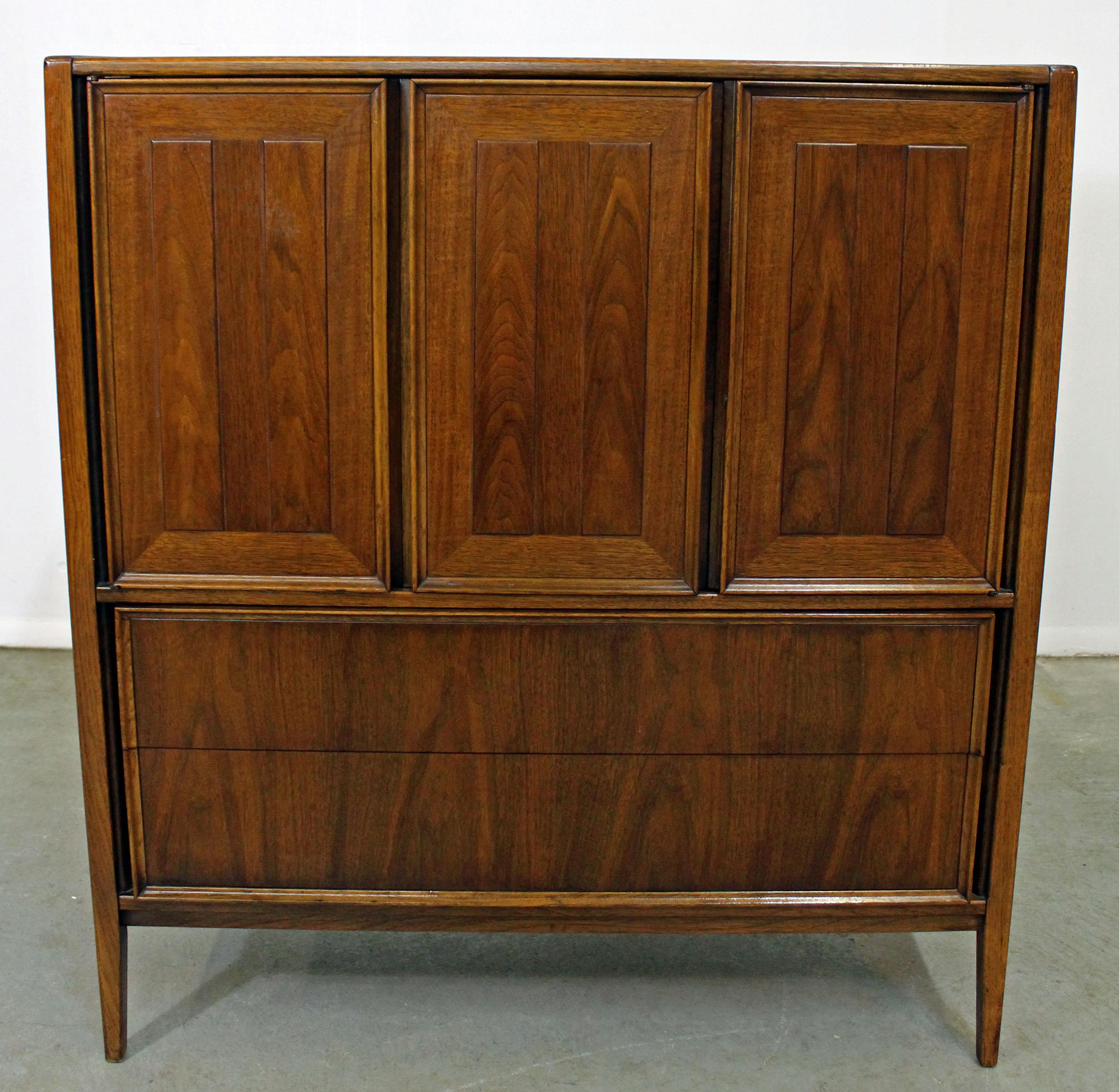 Offered is a Mid-Century Modern walnut tall chest or armoire. Includes five drawers altogether with three doors on top. Top drawer has a divider. It is in good condition, shows some wear (age wear, surface scratches/scuff marks- see photos), but
