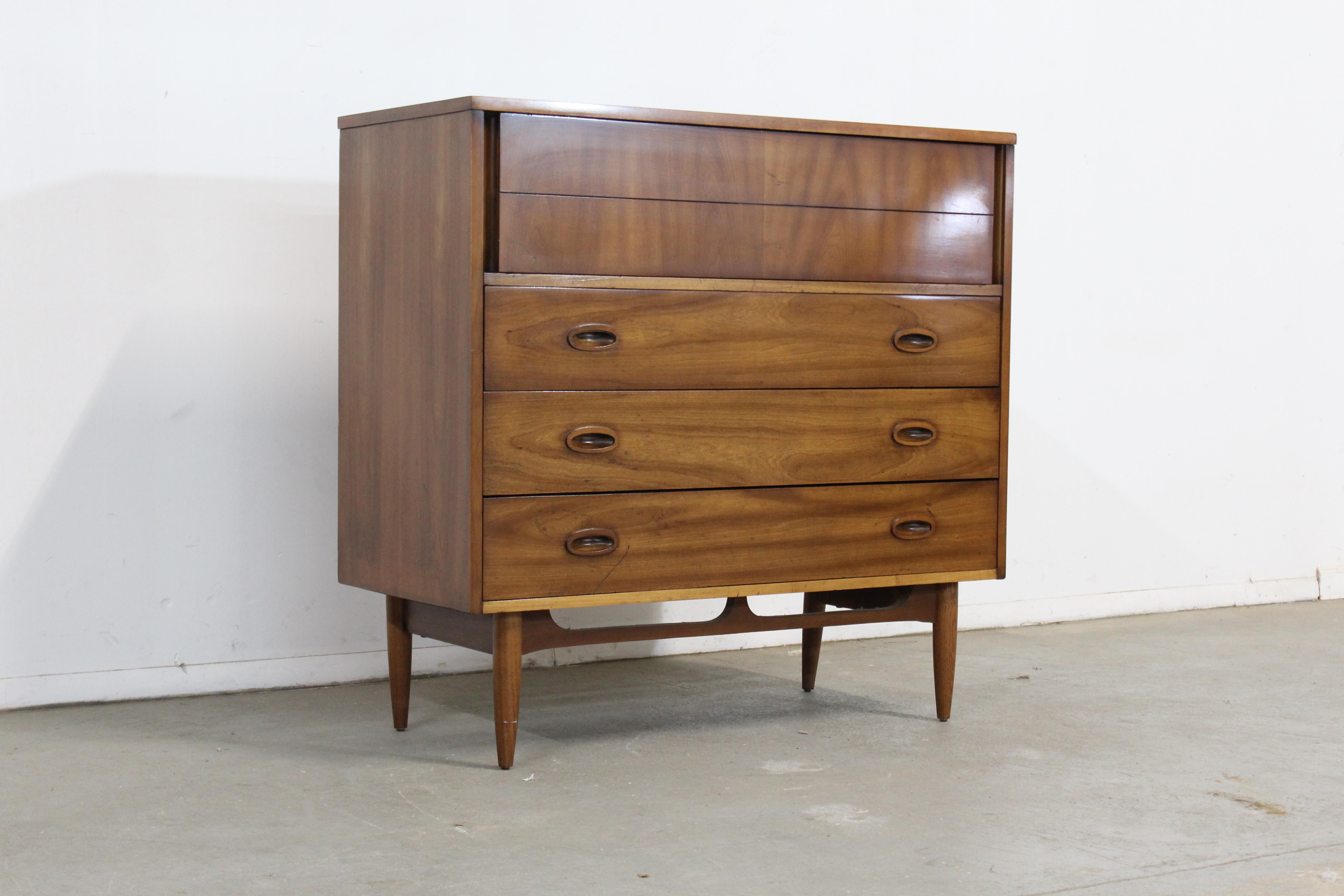 Mid-Century Modern walnut tall chest on pencil legs.

Offered is an excellent example of American mid-century modern design; a walnut dresser from the 1960's.The look is made by the beautiful stretcher base that accents the lines on this chest.