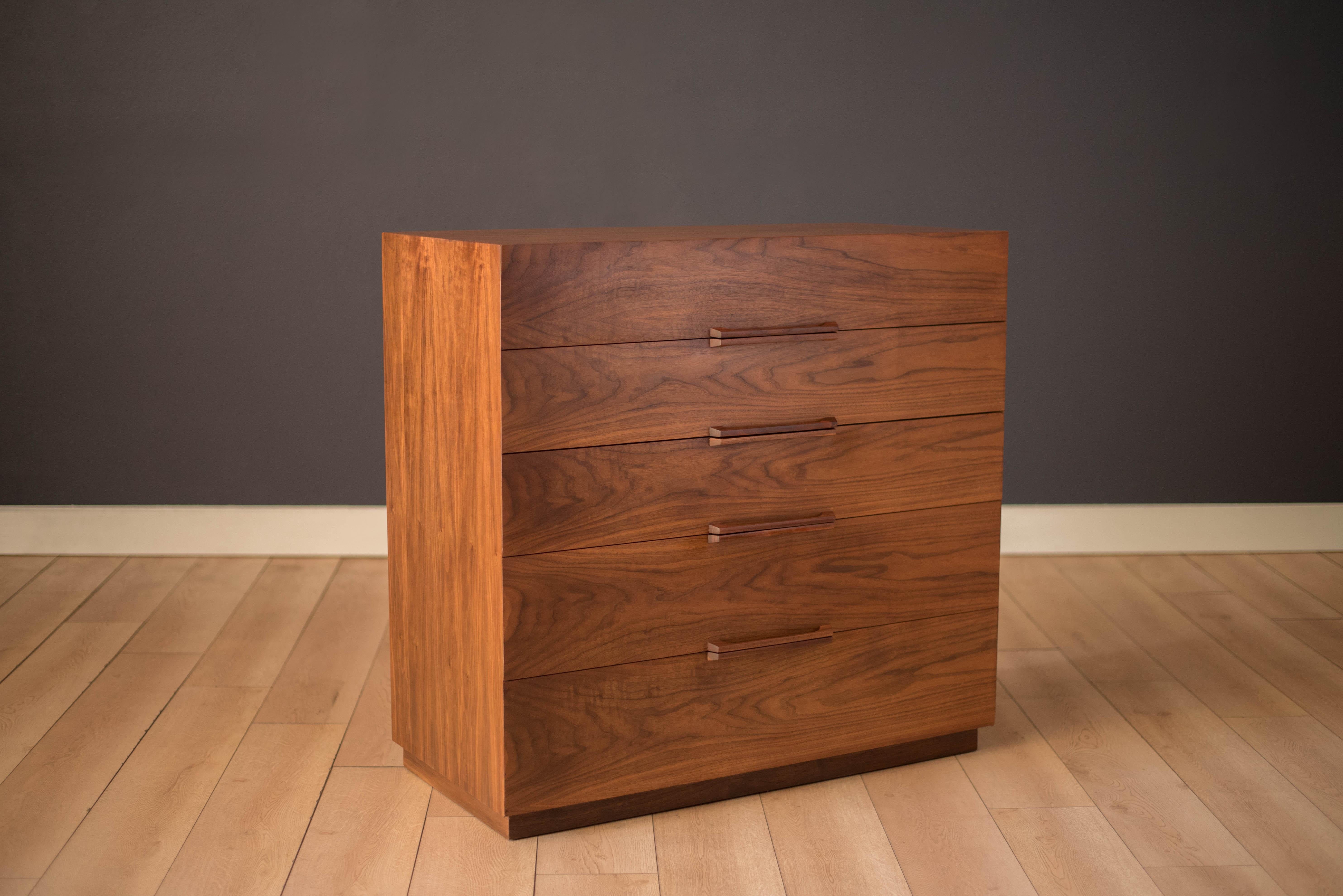 Vintage tall dresser in walnut manufactured by Ramseur Furniture Company, c. 1950's. This piece features a seamless beveled frame displaying bookmatched natural grains. Offers plenty of storage space including five drawers with dovetail construction.