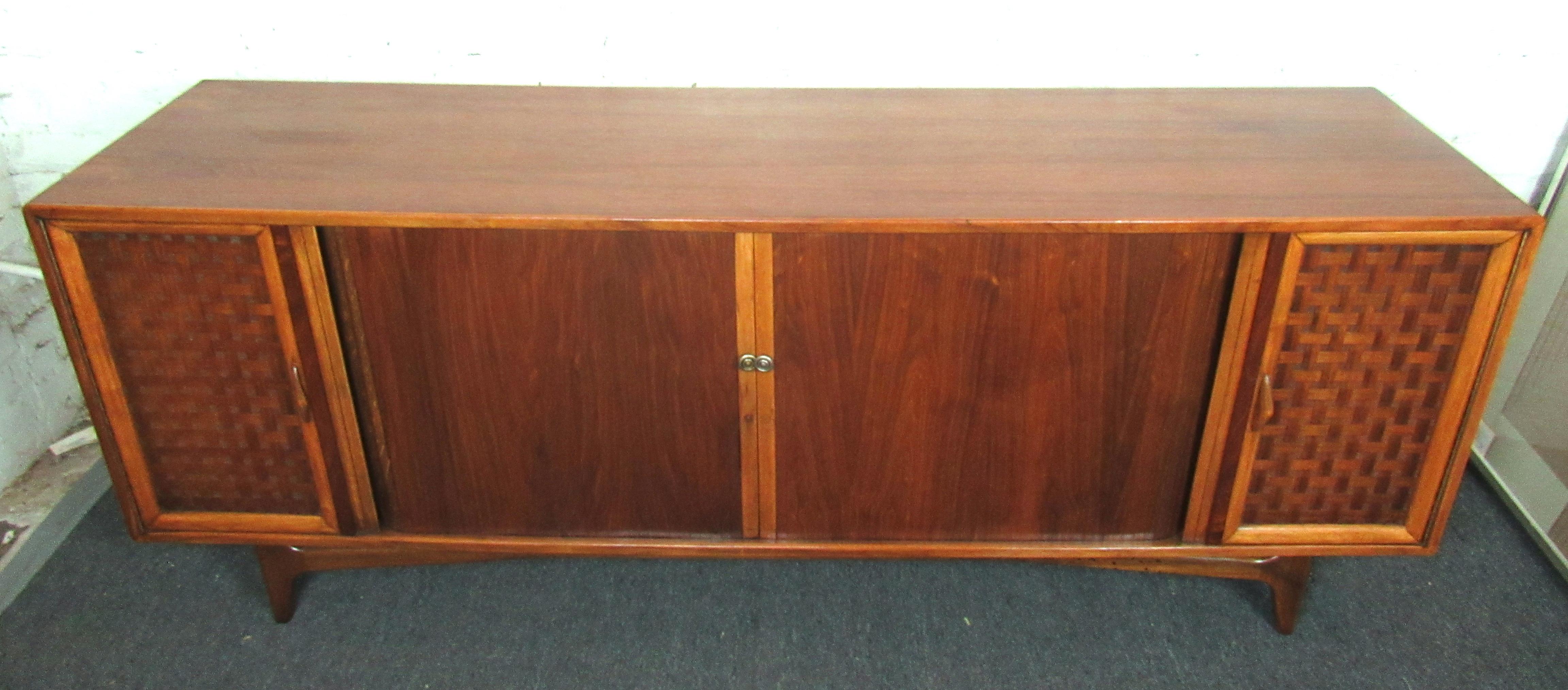 Beautiful vintage modern walnut sideboard by Lane. This piece features two tambour doors that conceal shelves for all of your storage needs, flanked on either side by woven style cabinets with sculptural wood handles.

(Please confirm item