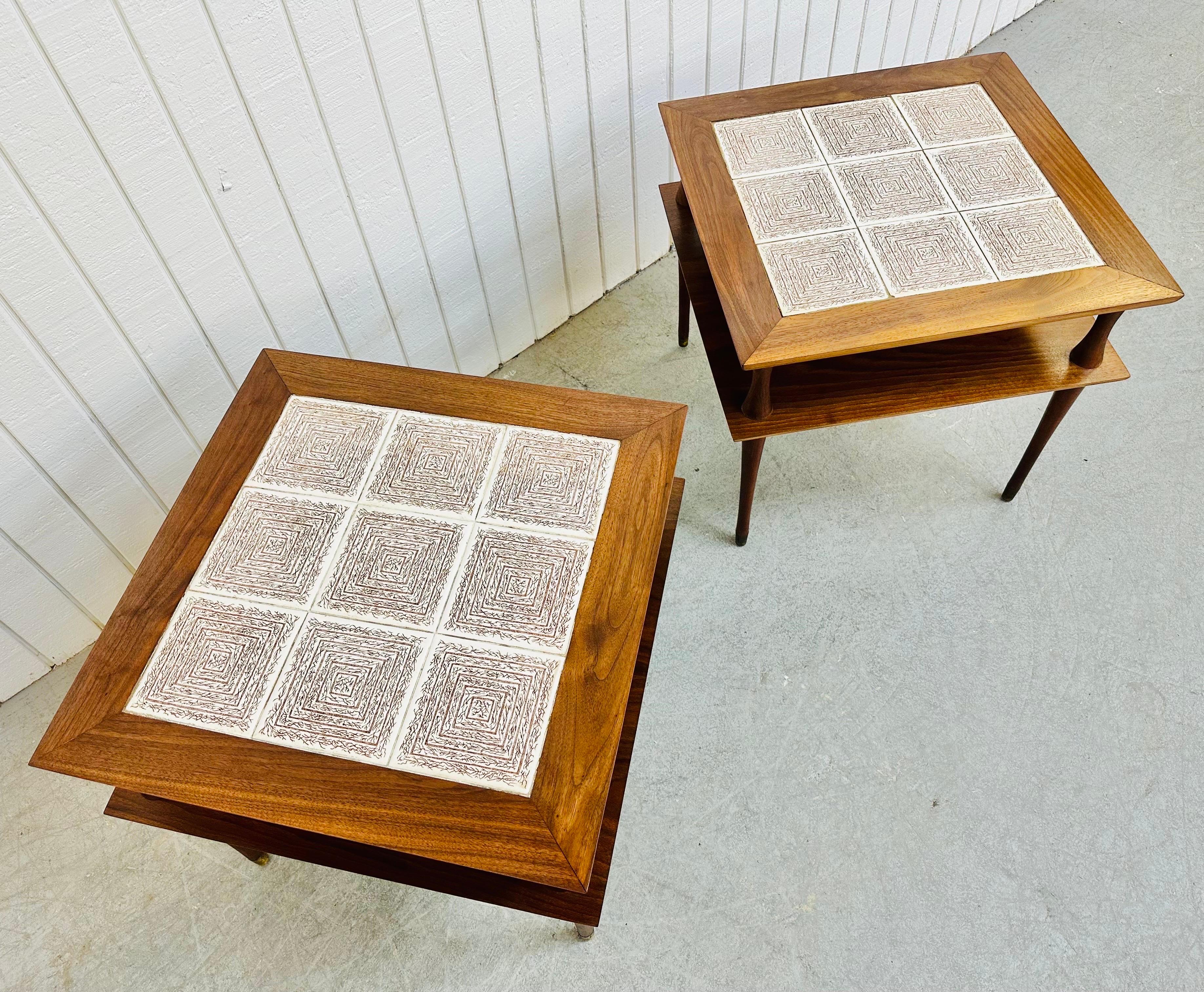 This listing is for a pair of Mid-Century Modern Walnut Tile Top Side Tables. Featuring a straight line square top design, bottom shelf for storage, original tiled top, long modern legs, and a beautiful walnut finish. This is an exceptional