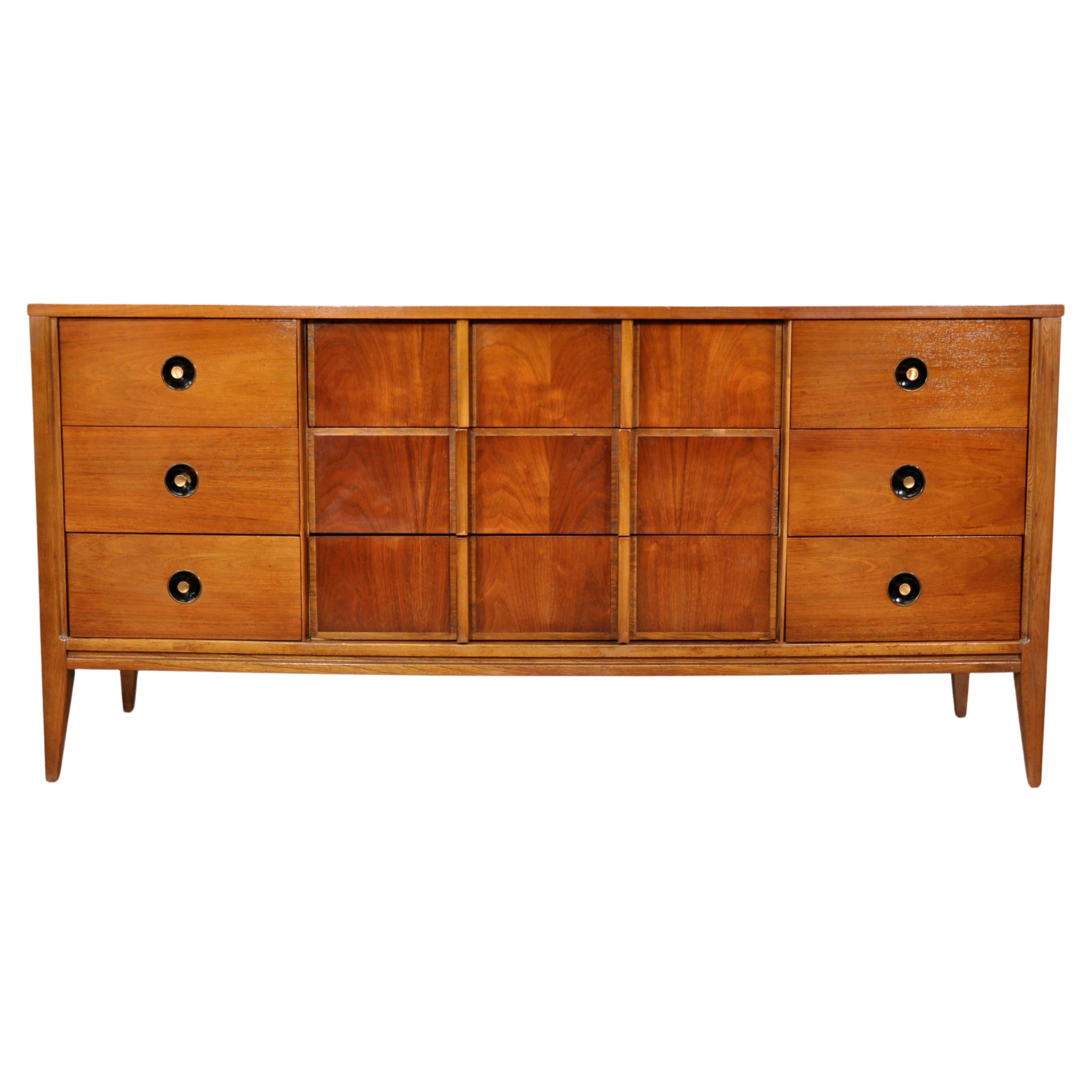 Vintage walnut and brass triple dresser by Stanley Furniture. The Mid-Century Modern credenza features 9 drawers, recessed black hardware with brass pulls, oak interiors and beautiful walnut grain. A ton of storage space with a ton of style!