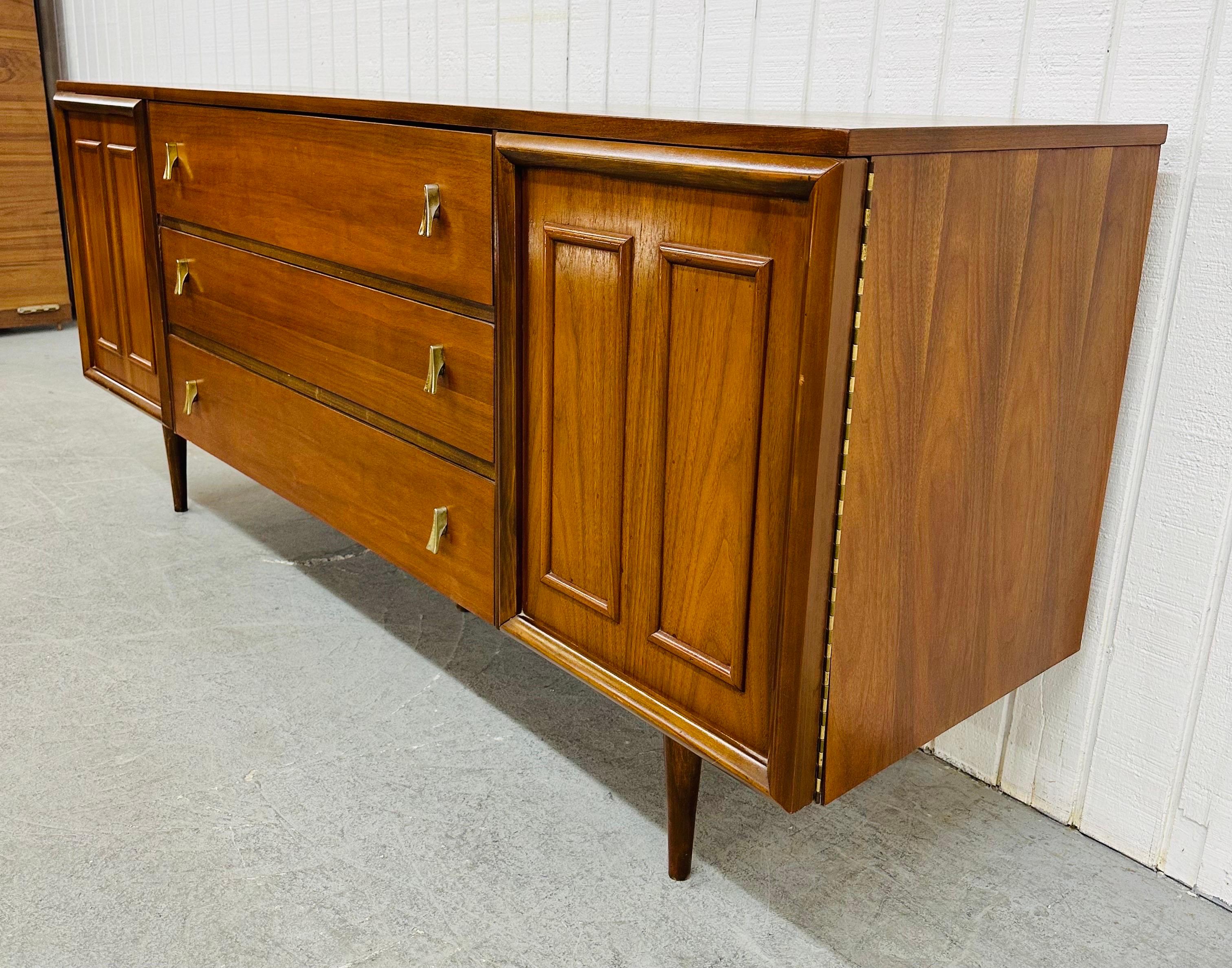 This listing is for a Mid-Century Modern Walnut Triple Dresser. Featuring a straight line design, doors on each side with walnut trim that open up to three hidden drawers, three larger center drawers with brass hardware, modern legs, and a beautiful