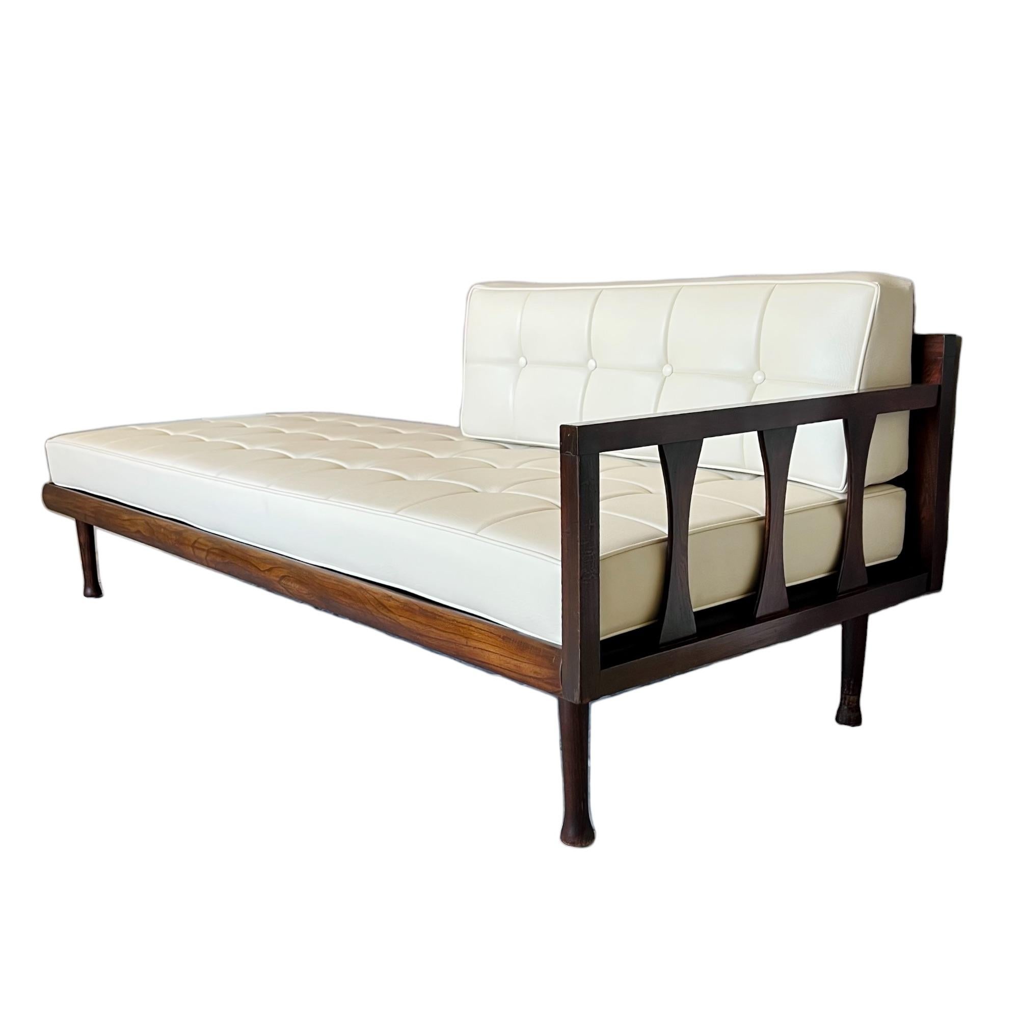 This sleek low profile vintage mid-century modern daybed style lounge sofa flaunts a minimalist design featuring walnut wood framing with a partial back rail and one side arm with vertical bowtie slats. The removable seat and back cushions are newly