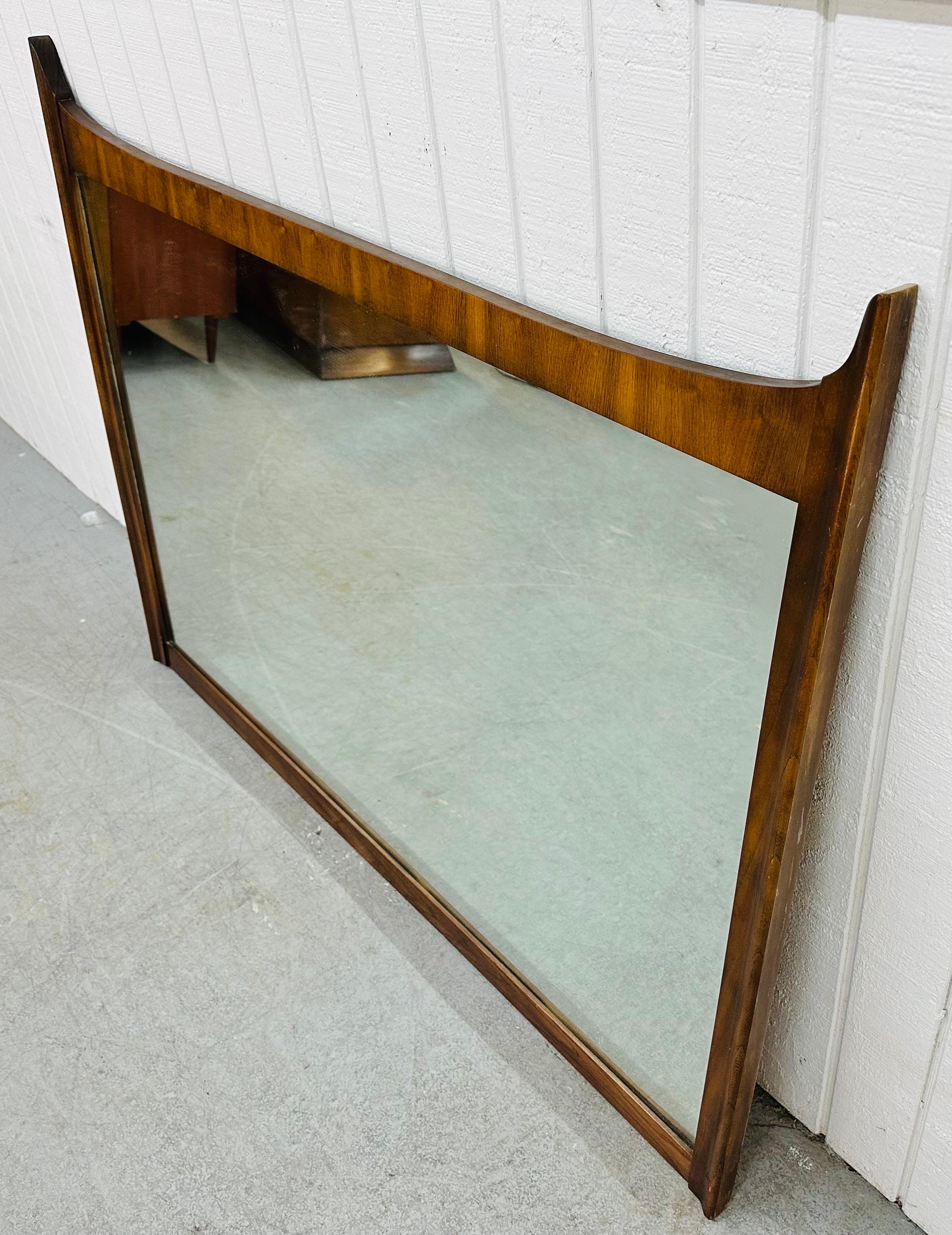 This listing is for a Mid-Century Modern Walnut Wall Mirror. Featuring a rectangular design, sculpted corners, and a beautiful walnut finish. This is an exceptional combination of quality and design!