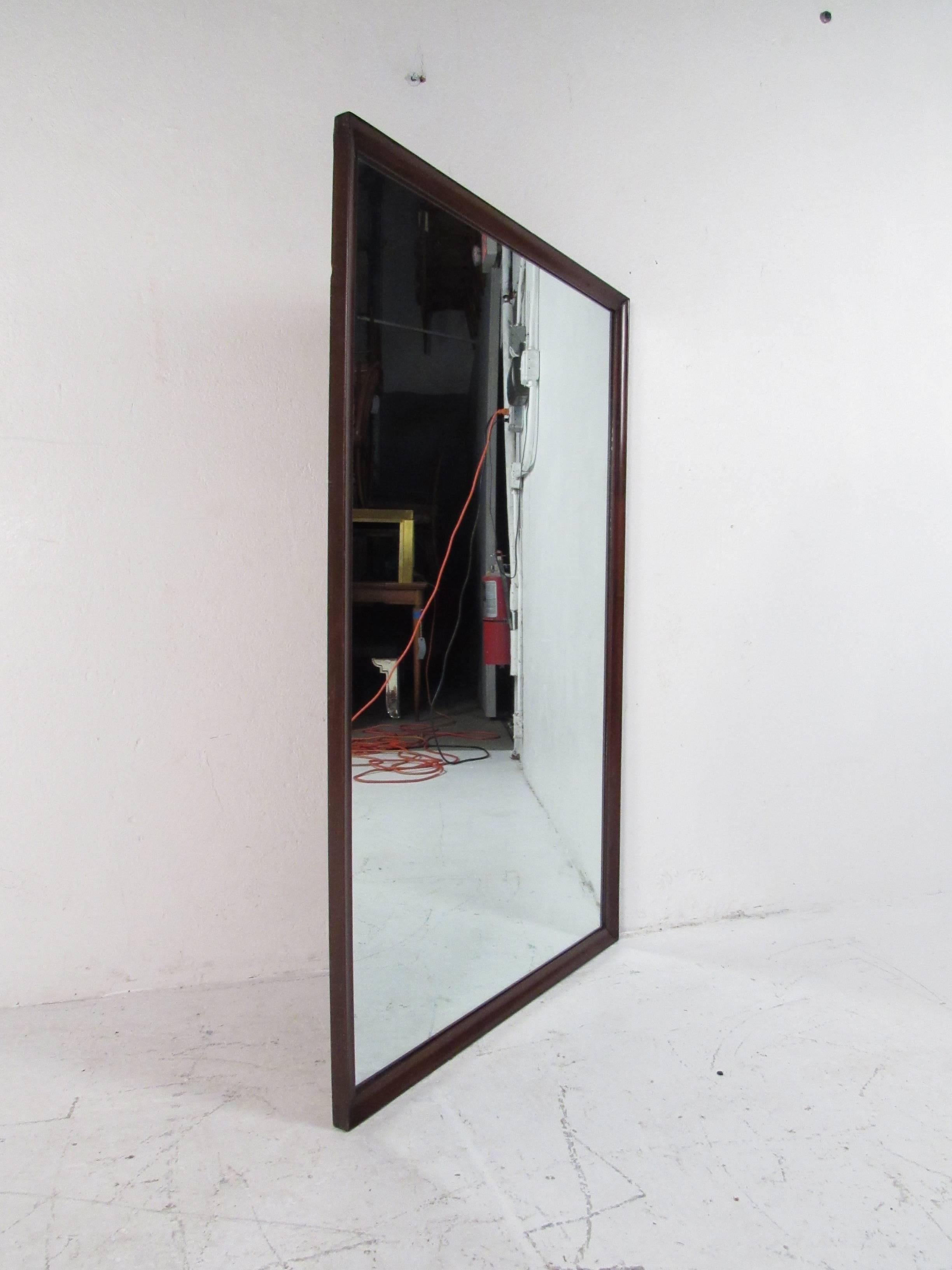 Un beau miroir moderne vintage avec un cadre en noyer foncé. Design épuré avec une forme rectangulaire et des bords biseautés. Cette pièce élégante du milieu du siècle est parfaite comme miroir mural ou fixée à l'arrière d'une commode. Veuillez