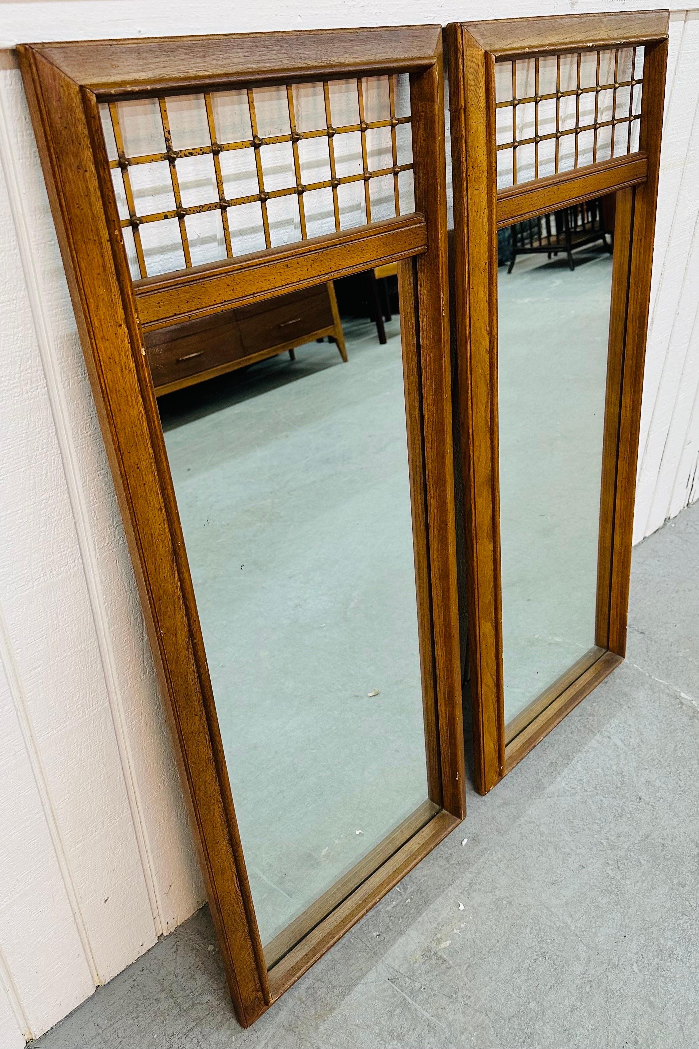 This listing is for a pair of Mid-Century Modern Walnut Wall Mirrors. Featuring a straight line rectangular design, brass fence along the top, and a beautiful walnut finish. This is an exceptional combination of quality and design!