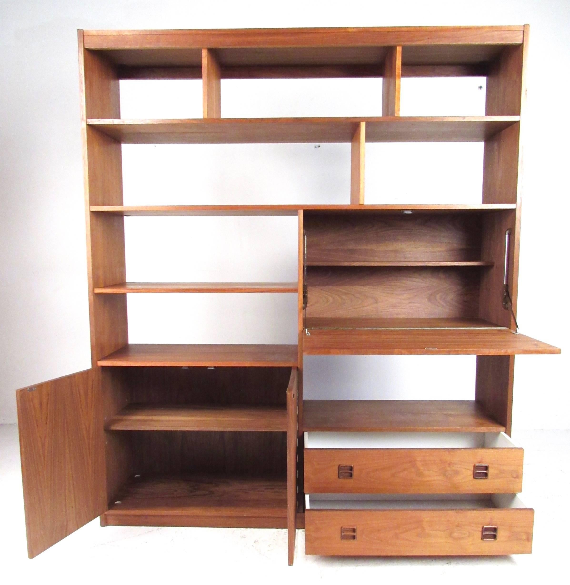 This beautiful midcentury wall unit features rich walnut finish and offers spacious storage options as well as a finished back. Adjustable shelves and spacious cabinets make this perfect for use as a bookcase, wall unit, or room divider, this pieces