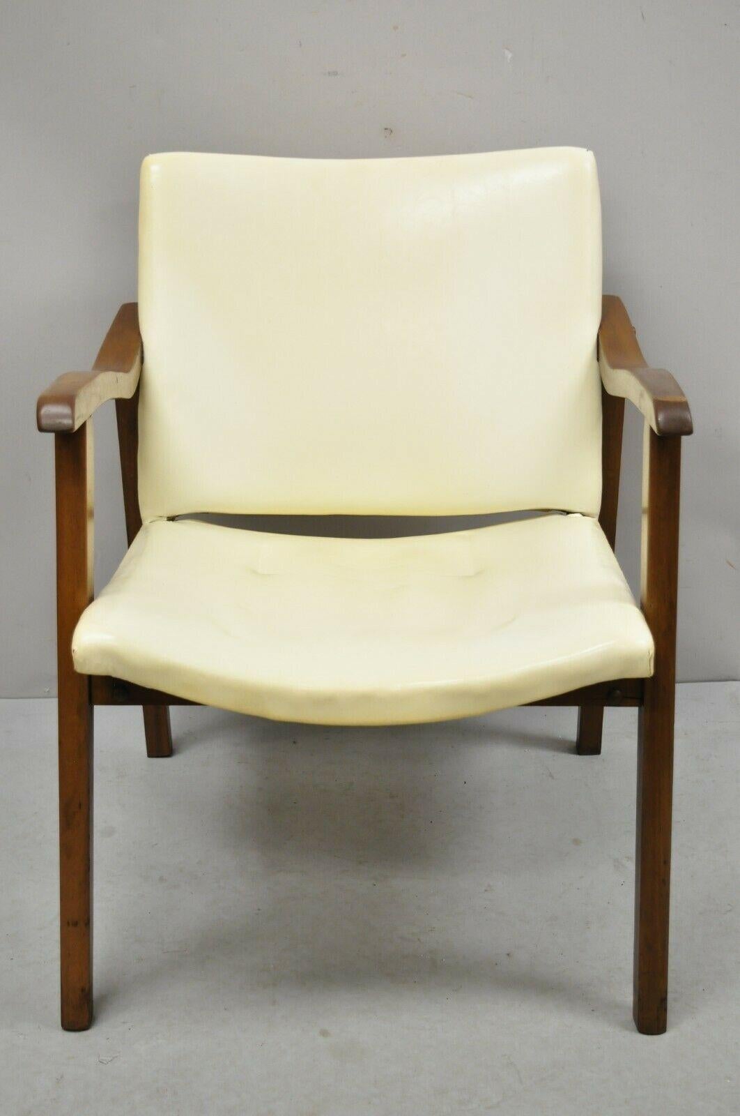 Mid-Century Modern walnut wood frame vinyl upholstered lounge arm chair. Item: features cream colored Naugahyde upholstery, solid wood frame, tapered legs, clean modernist lines, great style and form. Circa 1960s. Measurements: 28