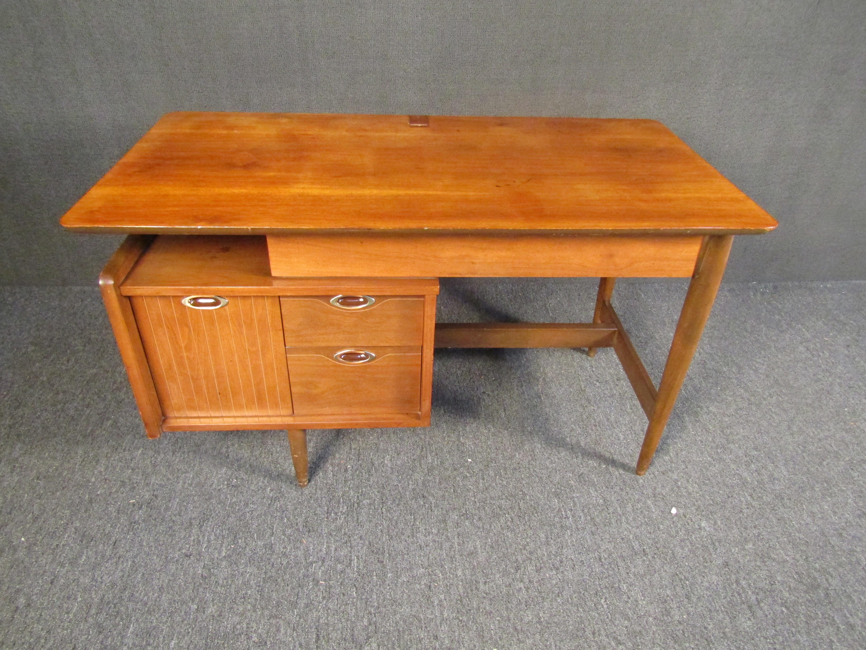 Elegant, functional, and full of mid-century quality, this vintage writing desk by Mainline stands out with its rich walnut woodgrain and stylish design. Spacious compartments allow for easy filing and storage, while a large writing surface makes
