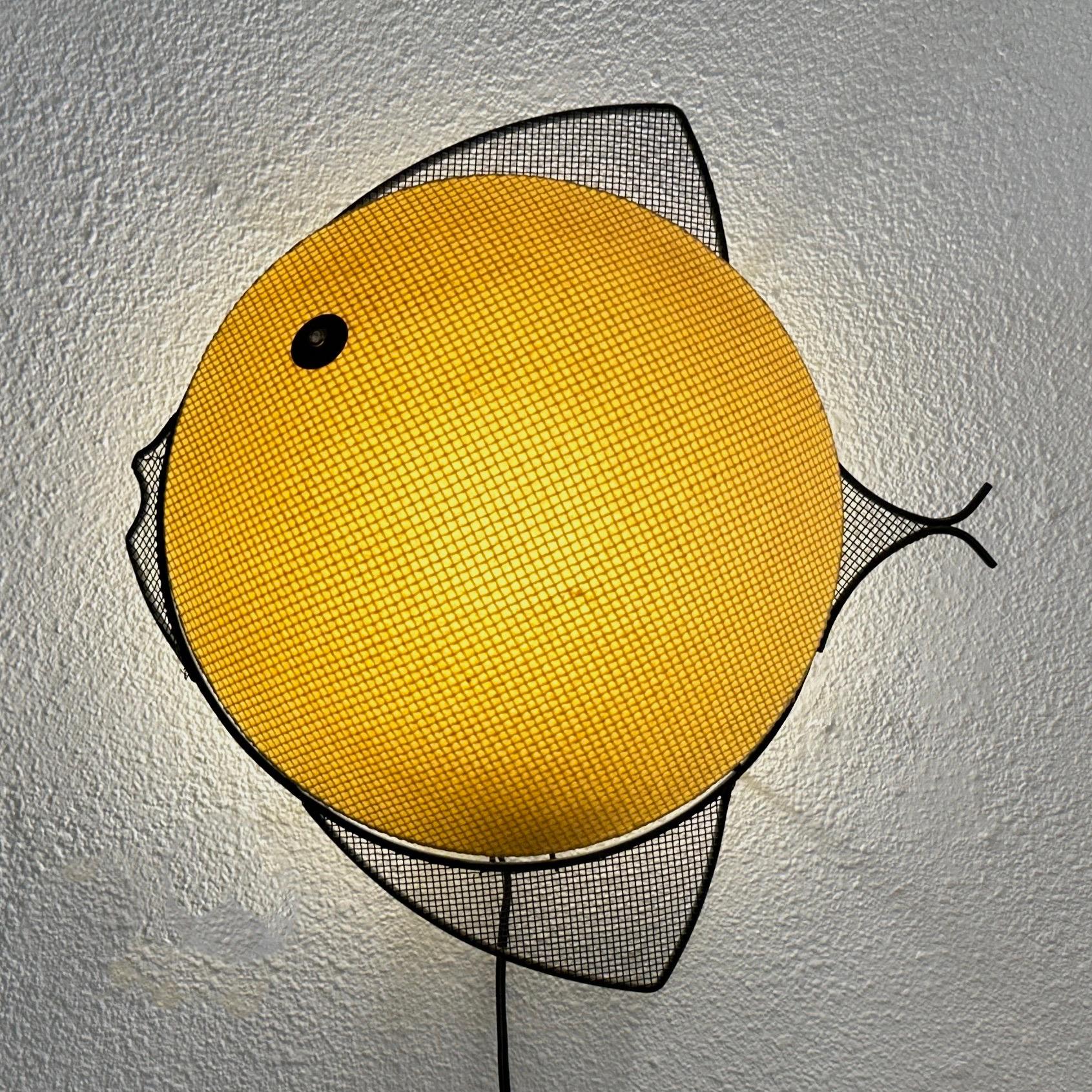 Mid Century Modern Weinberg Mategot Style Metal Fish Wall Lamp with a composite shade. The composite material seems to be a pressed paper of some sort similar to fiberglass but quite sturdy as it has lasted many years. I would suggest using a lower