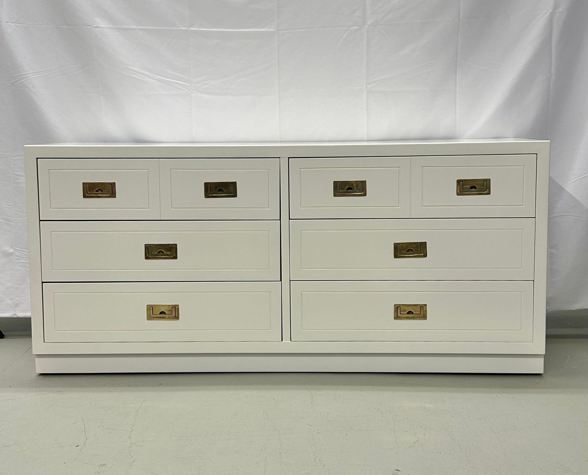 Mid-Century Modern white Campaign Dresser / chest of drawers, America, brass.
A fine example of campaign furniture done over in a white lacquered finish. The case having nine drawers all with hidden brass handles sitting on a bracket base. 
gsx.