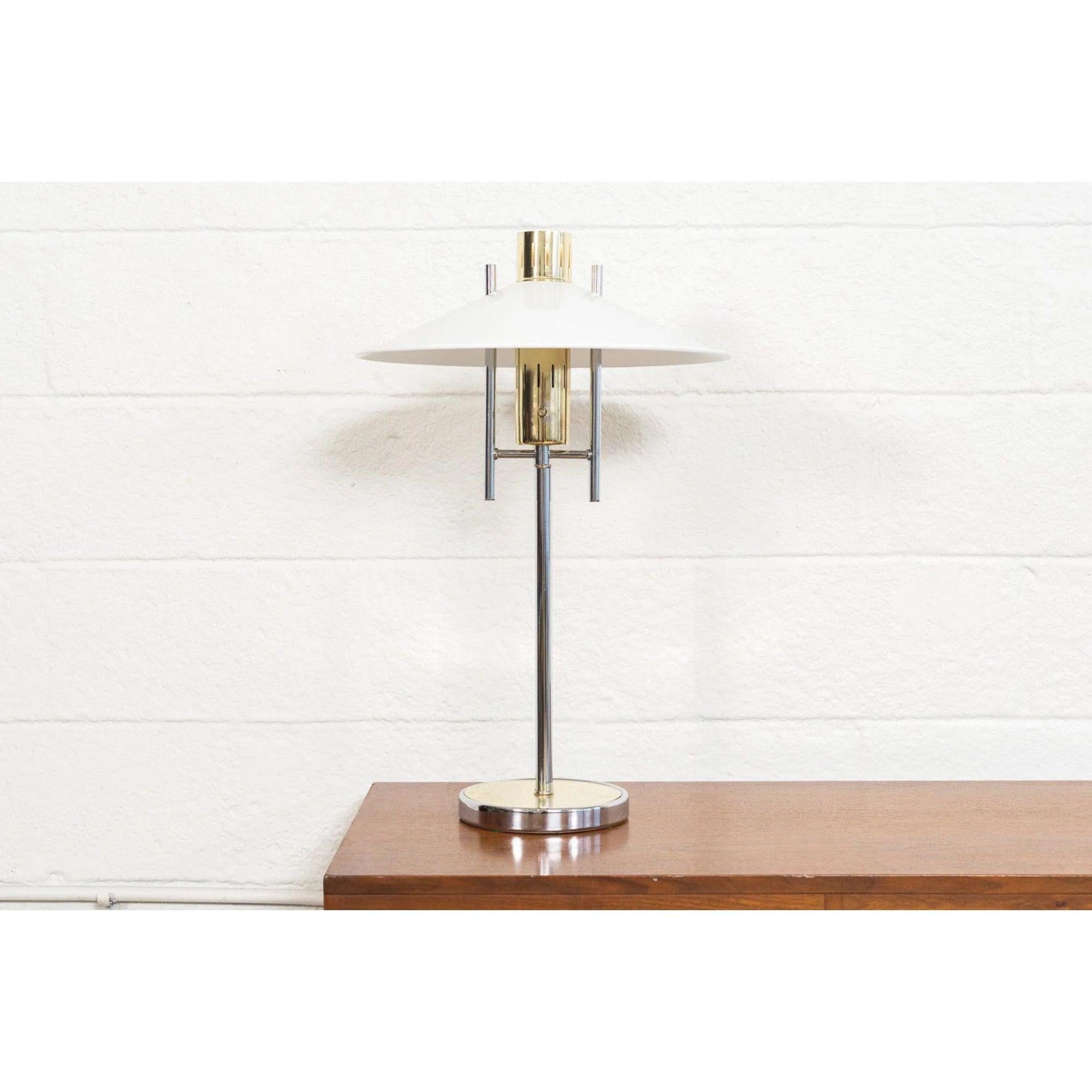 This unique vintage Mid-Century Modern table lamp is circa 1970. The clean, modernist design features a tubular polished chrome stem with brass accented at center and base and a white metal triangular shade. Lamp has three-way switch.

Additional