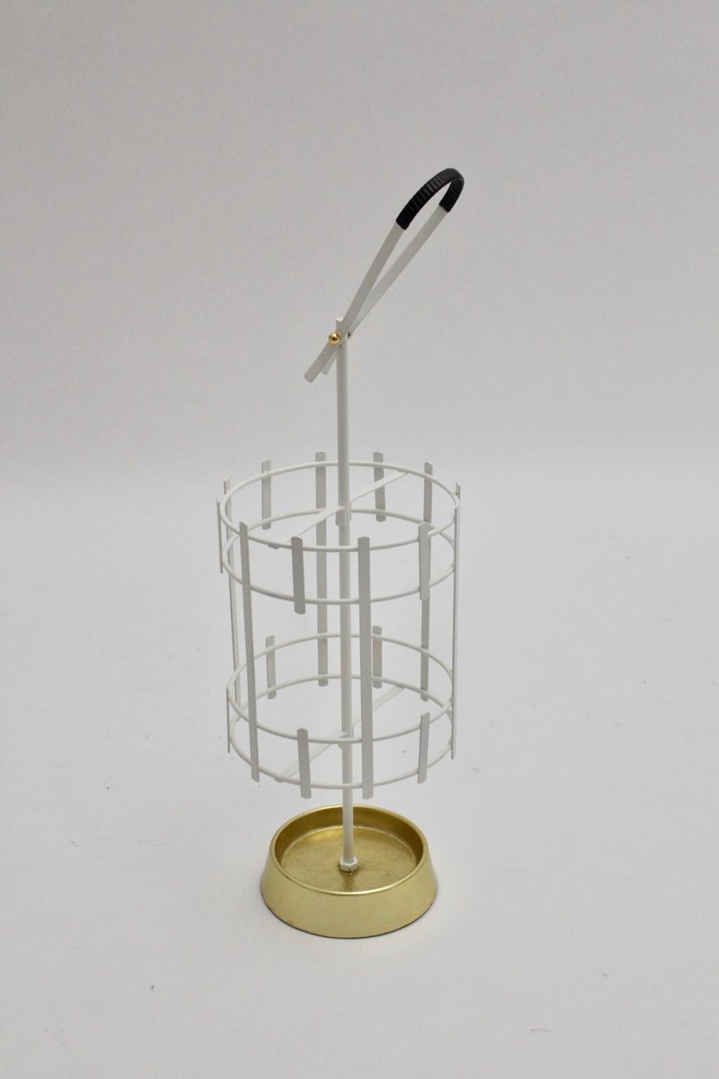 The stunning mid century modern vintage umbrella stand from the 1950s was made of white lacquered metal basket, brass fittings and cast iron. Also the umbrella stand was carefully cleaned and the metal basket is newly lacquered, so the vintage