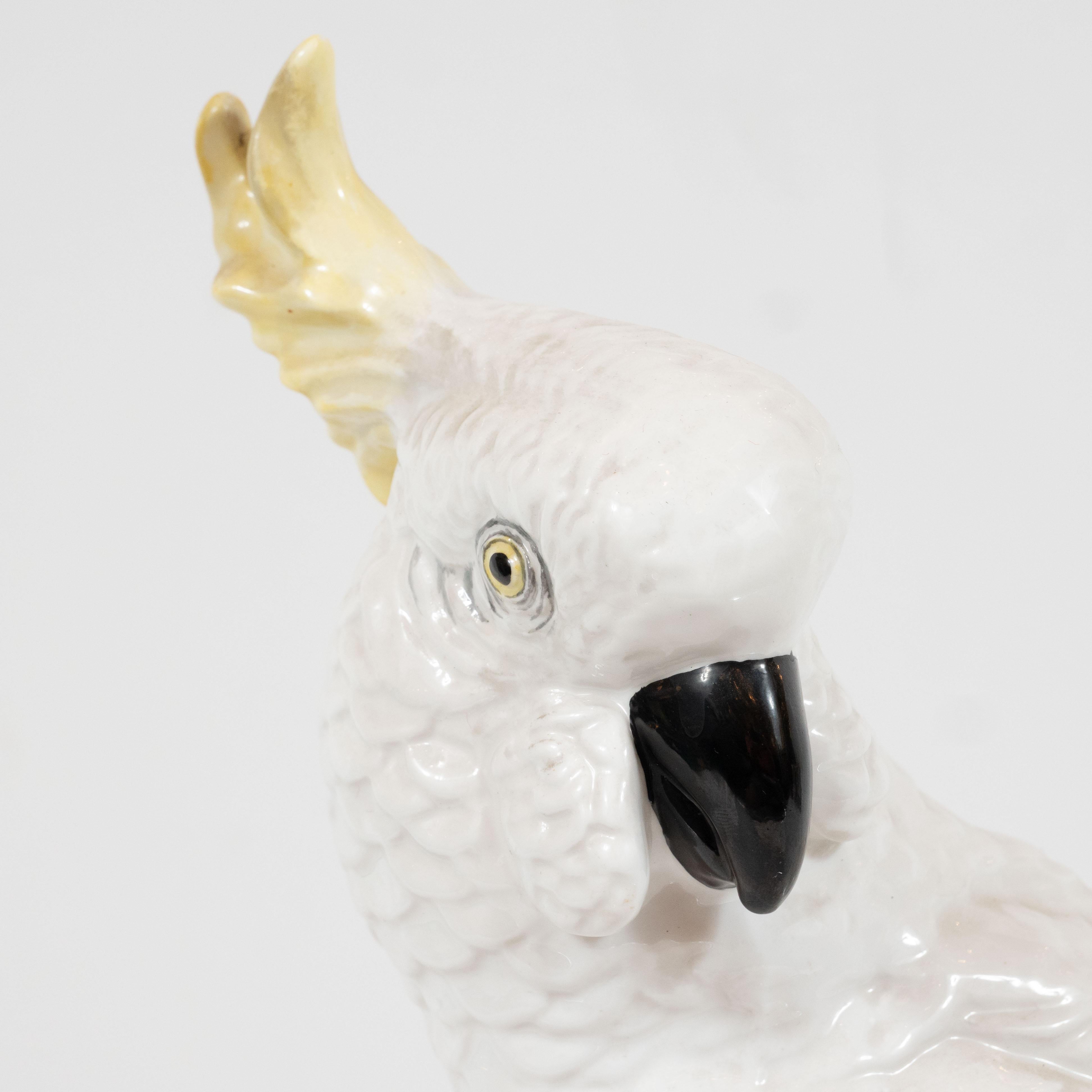 This elegant Mid-Century Modern fine bona china cockatoo was designed by T.J. Jones for Staffordshire, the storied British maker, circa 1950. It features a white cockatoo perched on a sculptural base with foliate detailing. The bird's head is