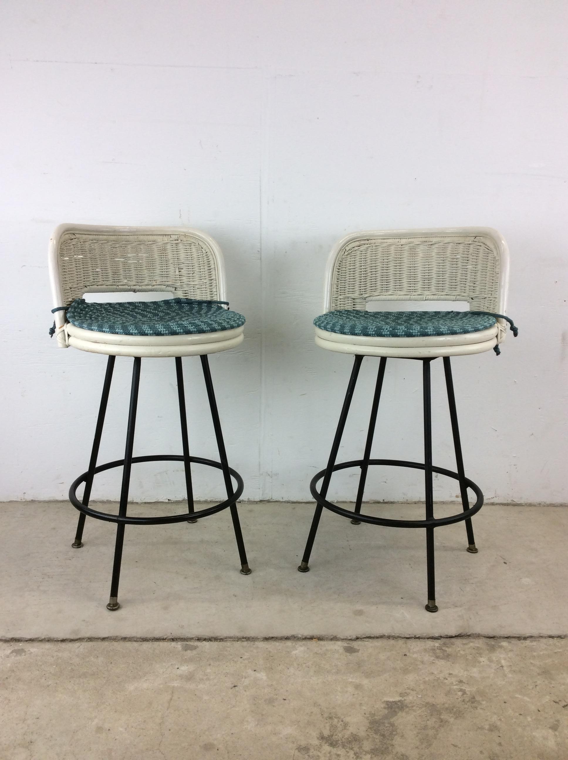 This pair of mid century modern bar stools in the style of Arthur Umanoff feature white painted wicker construction with swivel seat atop a black painted metal base.

Dimensions: 17.5w 17d 32h 14sh

Condition: Wicker seats are in very good