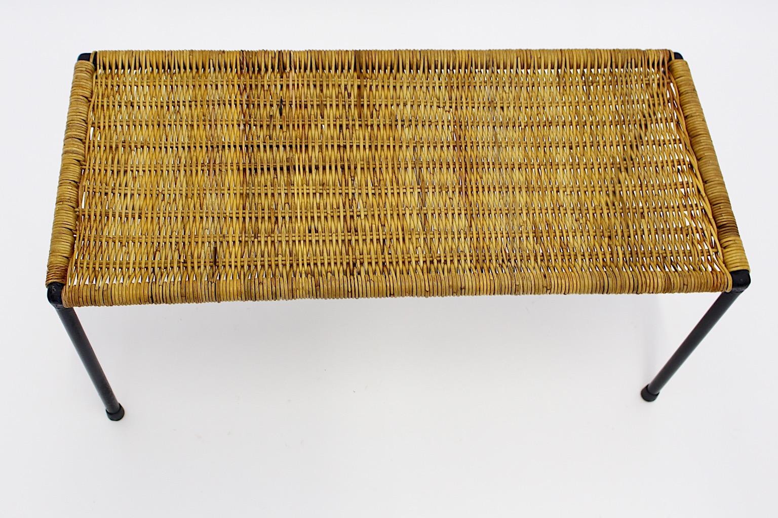 A Mid-Century Modern wicker rattan side table or sofa table, which was designed and manufactured in Austria, 1950s.
While the table frame was made of black lacquered tube steel, the tabletop shows handwoven wicker top.
Throughout its rattan top it