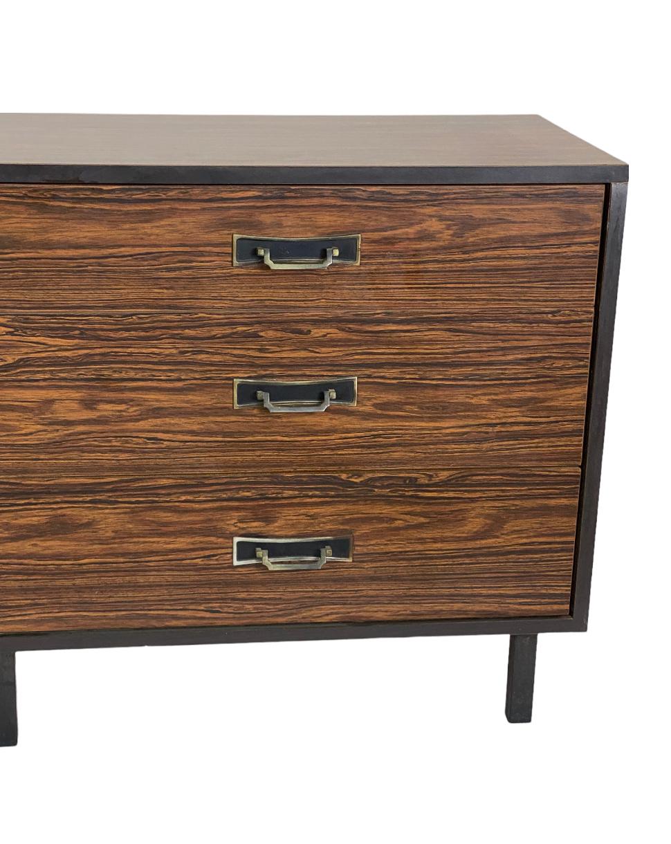 Gorgeous Mid-Century Modern chest of drawers. Rosewood grain laminate surface provides durability and is less prone to moisture and surface wear. Gorgeous color and lines. Original brass pulls intact with lovely patina. Drawers open easily to