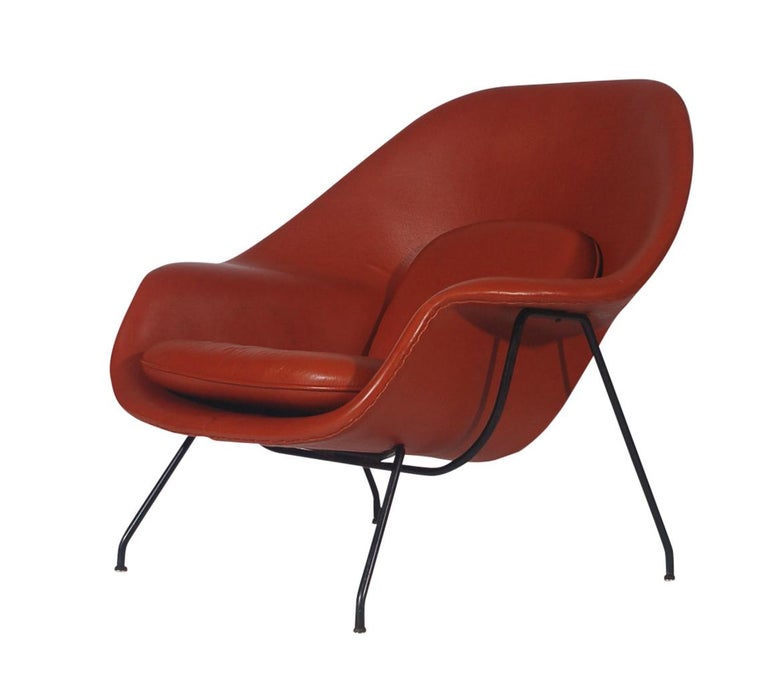 A nice early 1950s womb chair and ottoman designed by Eero Saarinen and produced by Knoll. The chair was redone in dark cognac colored leather in the early 2000s. Black frame original and has age appropriate wear. Overall very good condition.