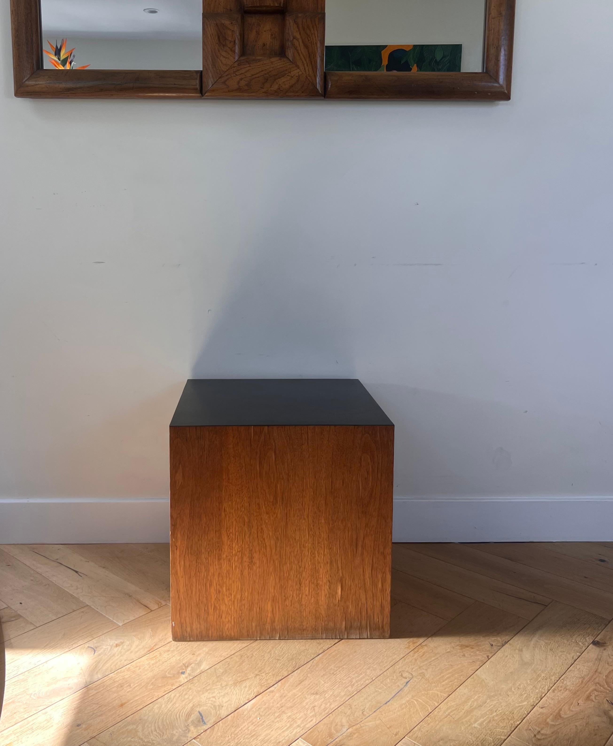 A modernist wood veneer and laminate cube pedestal / end table, circa 1970. One side is black laminate, the other side is white laminate.
Some of the veneer is rippling here and there, but otherwise good vintage condition. Pick up in central West