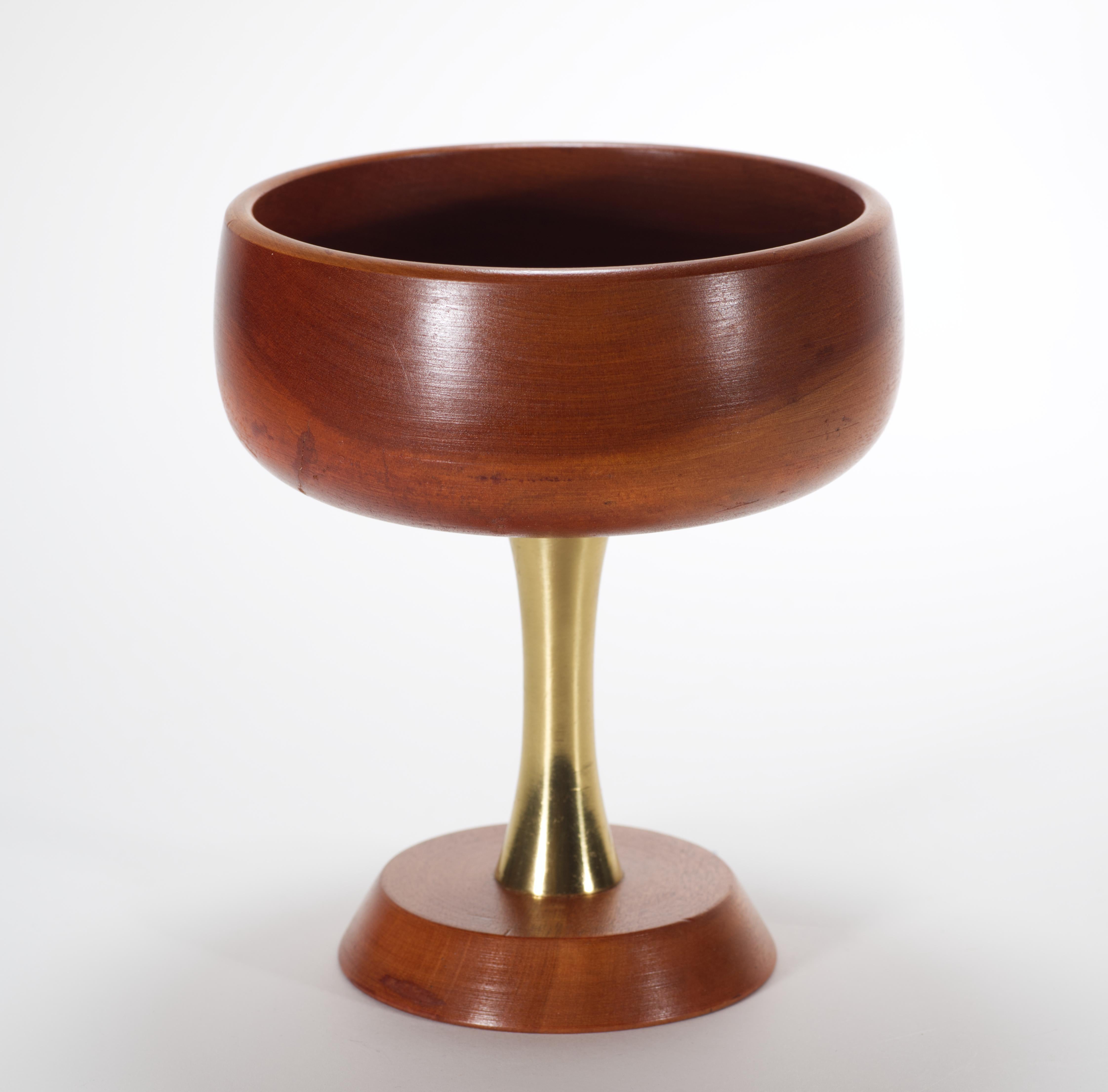  Vintage Modernist footed bowl features wooden bowl and base and sculptural brass foot. The wood has beautiful grain and age-appropriate patina.

The bowl is signed on the bottom with the original foil sticker 