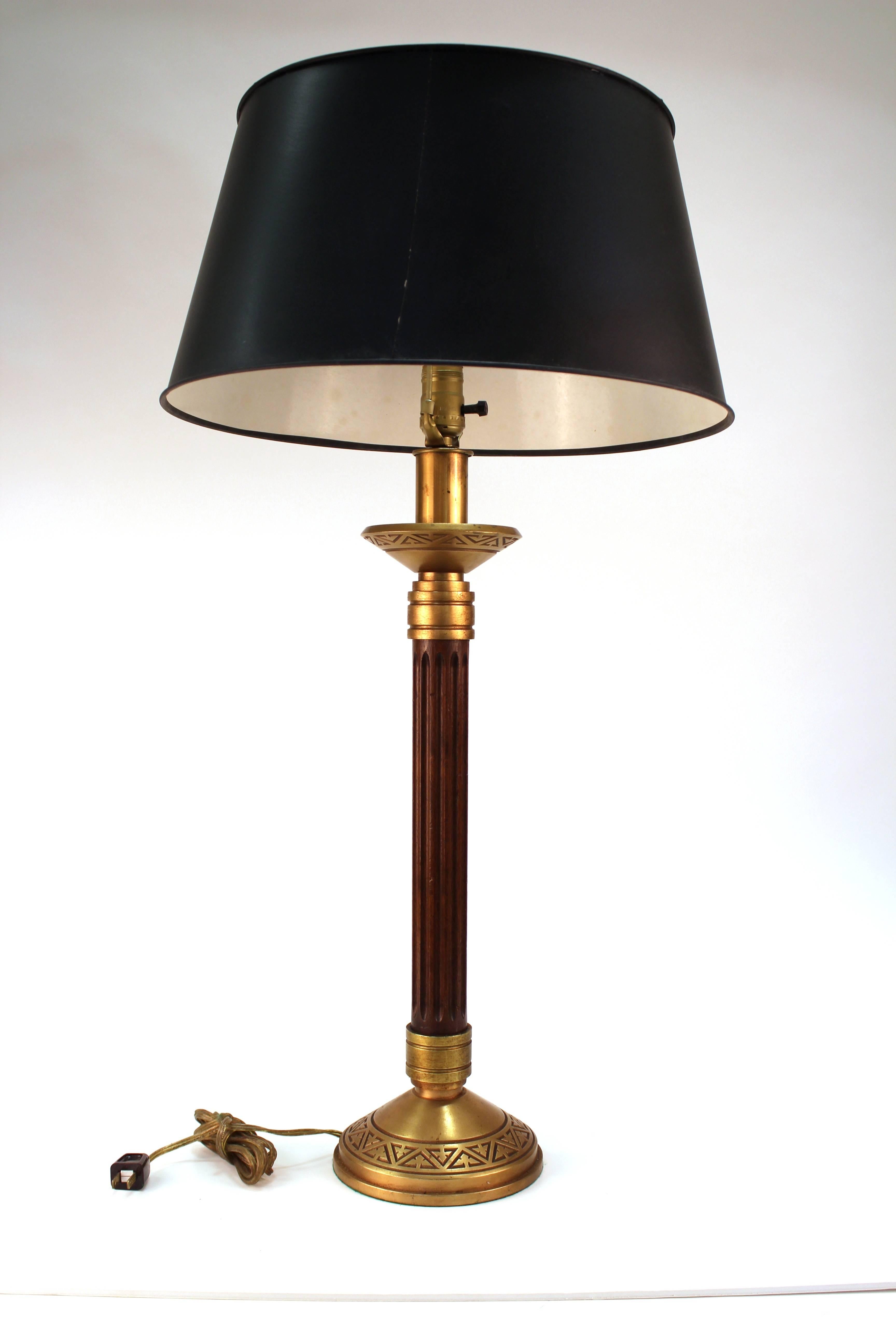 A midcentury pair of table lamps with wooden fluted column shafts and heavy brass base and crown with sculpted Greek key decorative elements. The pair comes with black shades and was made in the 1940's in the United States. In very good vintage