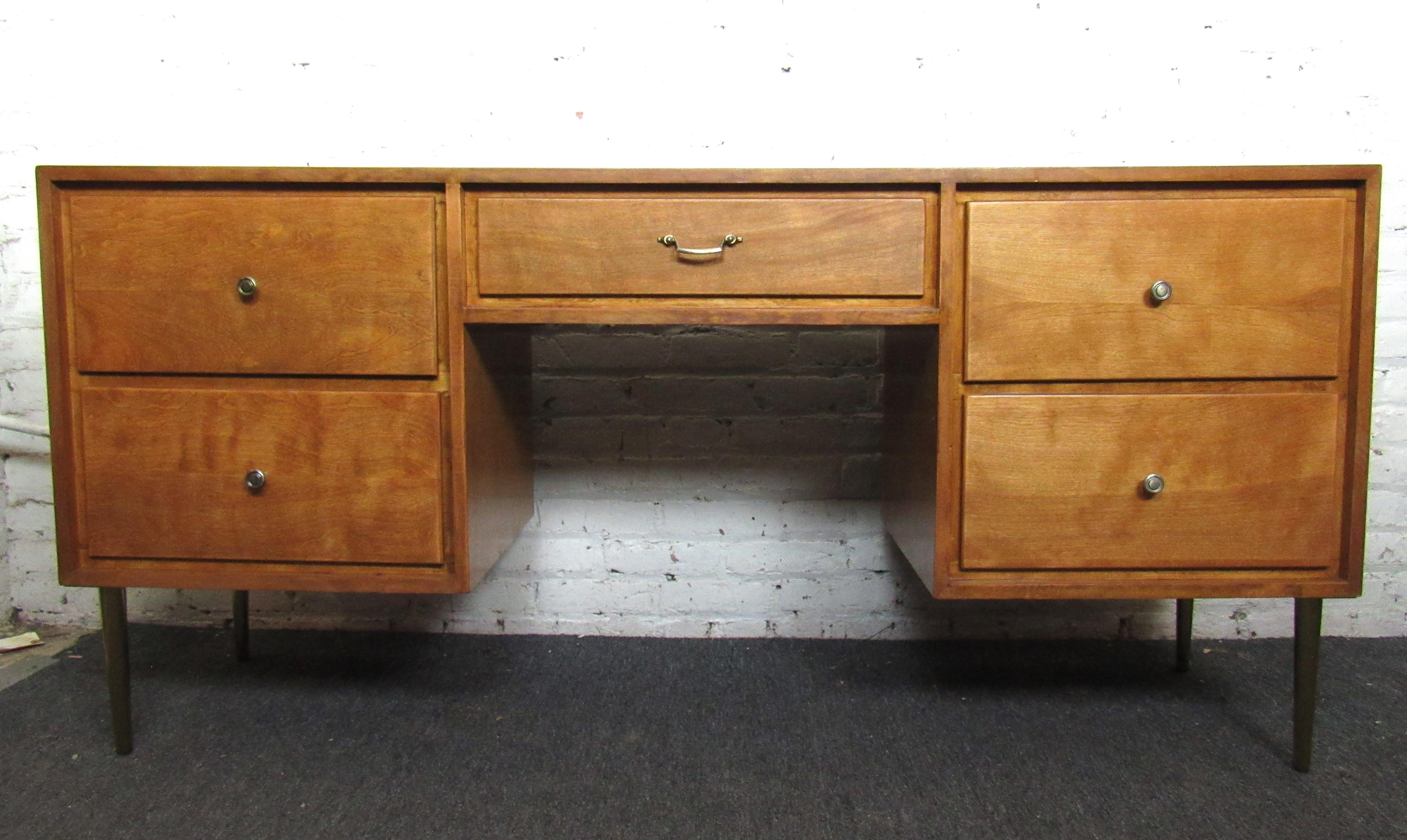 Beautiful vintage modern executive desk. This desk features four large drawers on either side of the desk, with a desk drawer in the middle. The wood is finished in a rich warm blonde color. New brass colored legs were added to the piece to