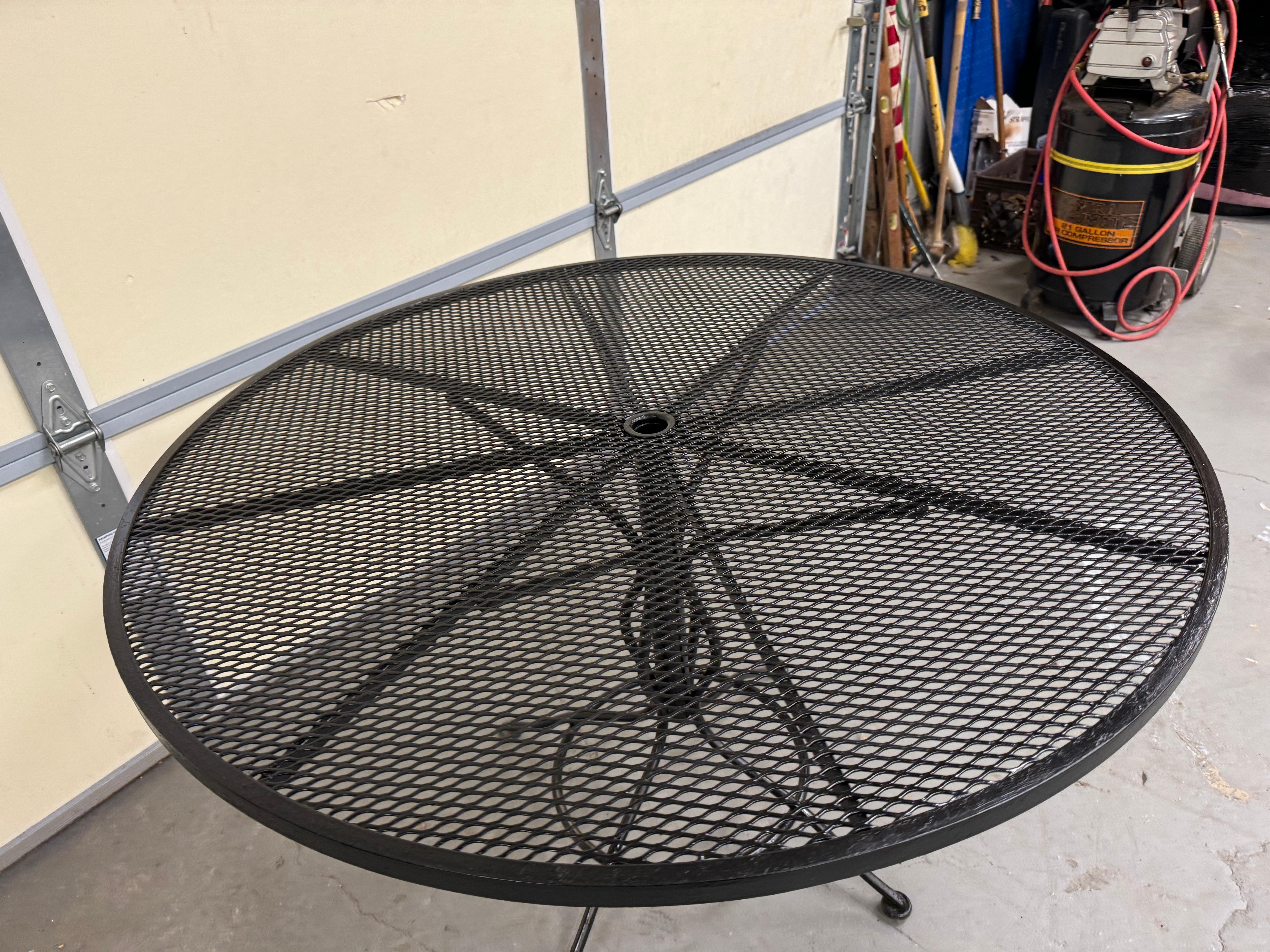 Mid-Century Outdoor Iron Woodard Round Dining Table 
Offered is a mid-century outdoor iron dining table by Woodard. The table is round and features a decoarative base, black paint and woven wrought iron. The table is structurally sound in good