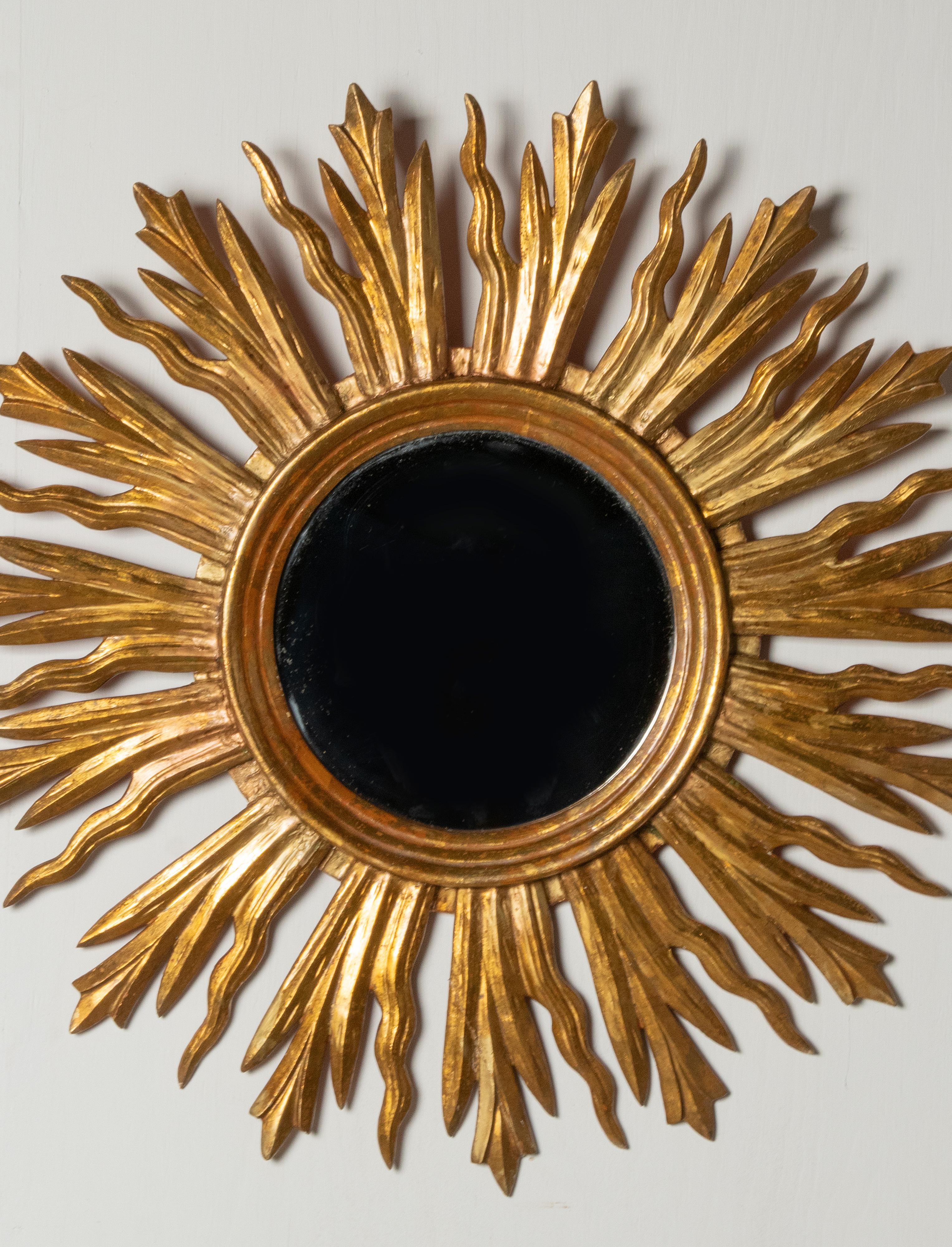 Large gilded sunburst mirror with beautiful wooden carved rays. The mirror glass is flat, and have no stains and wear. The mirror dates from circa 1950-1960, from France. This mirror is entirely made of wood.