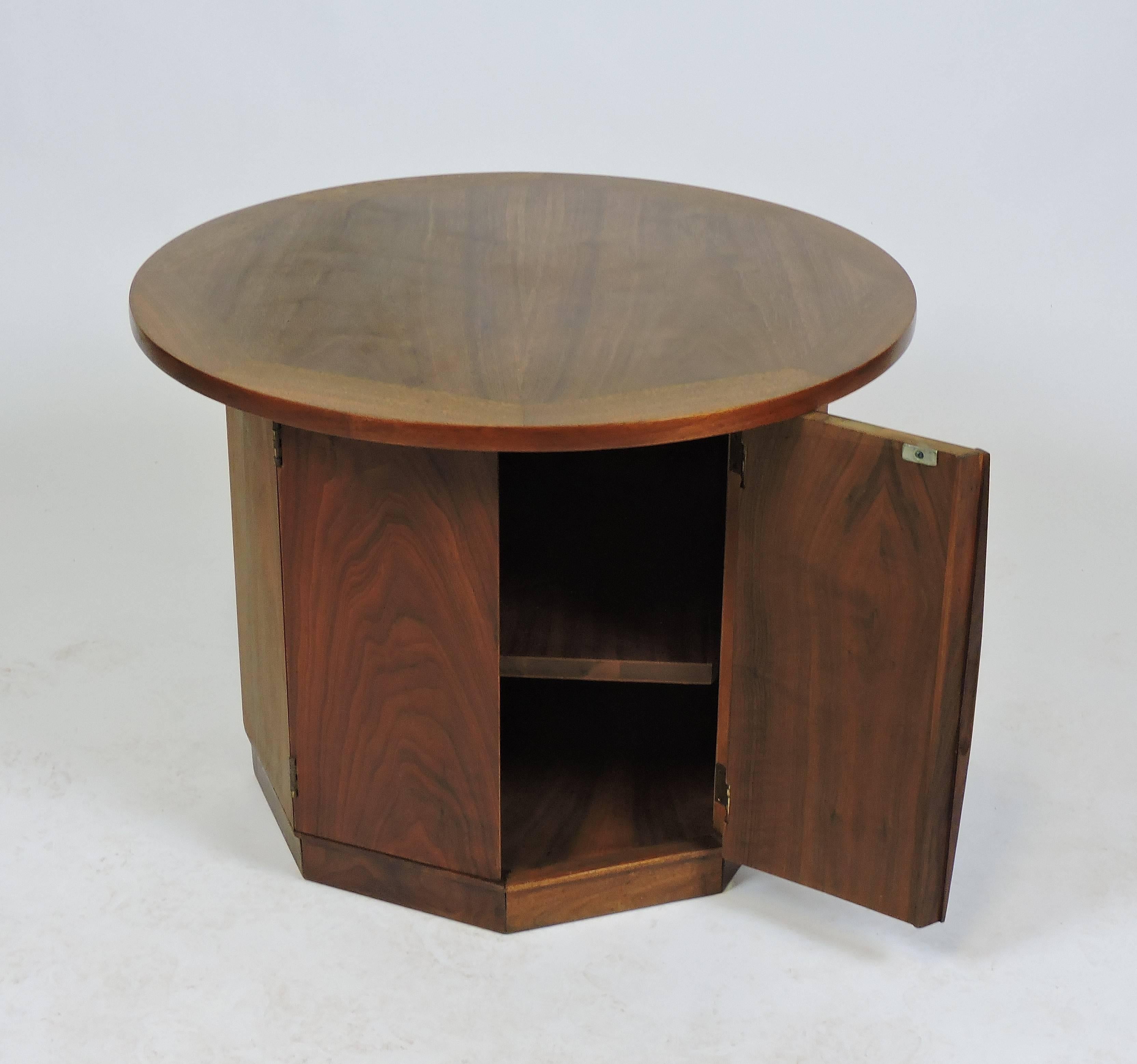 Handsome Ed Wormley style midcentury walnut end table/cabinet. This table has a round top with a hexagonal base with two doors that open up for storage. It has beautiful wood grain and an interior adjustable shelf.