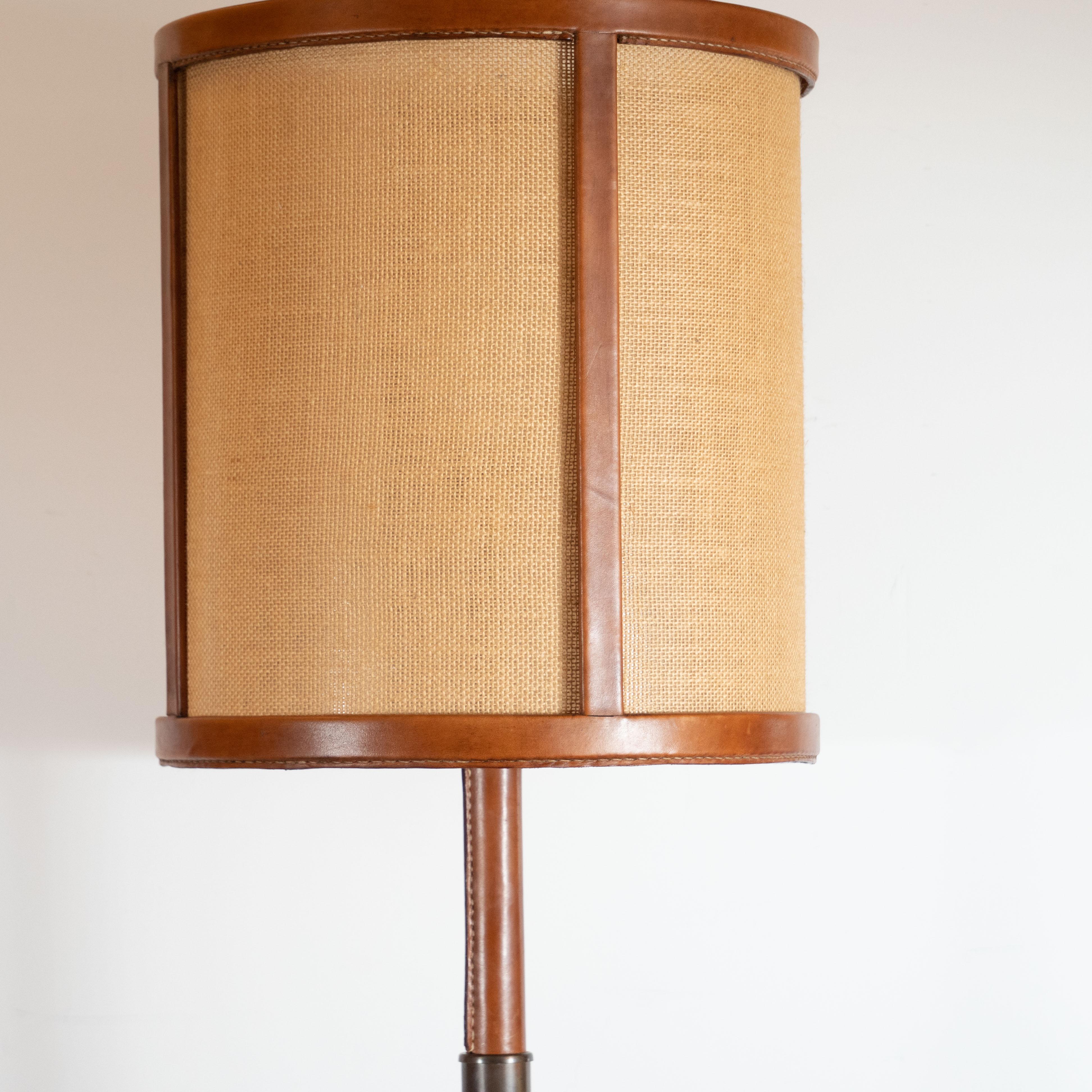 This sophisticated Mid-Century Modern floor lamp was designed in France, circa 1950. It features a bronze circular base with a cylindrical body ascending from the center. The lower portion of the body is bronze, while the majority of the cylindrical
