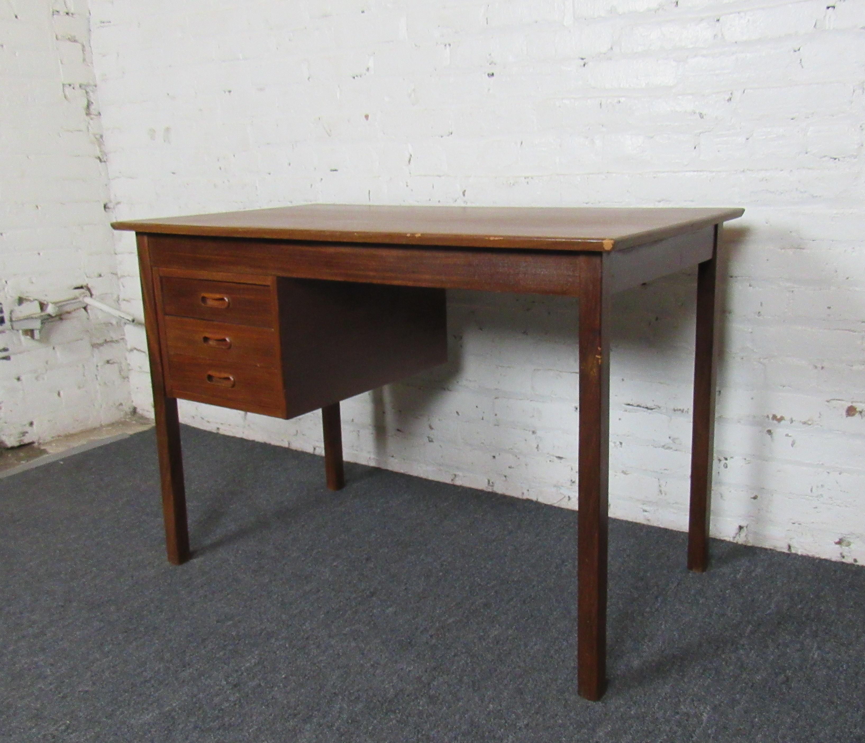 This vintage writing desk combines sturdy Mid-Century Modern quality with simple elegance. With three drawers for storage, this desk is perfect for adding tasteful style to a home office or business. Please confirm the item location (NY or