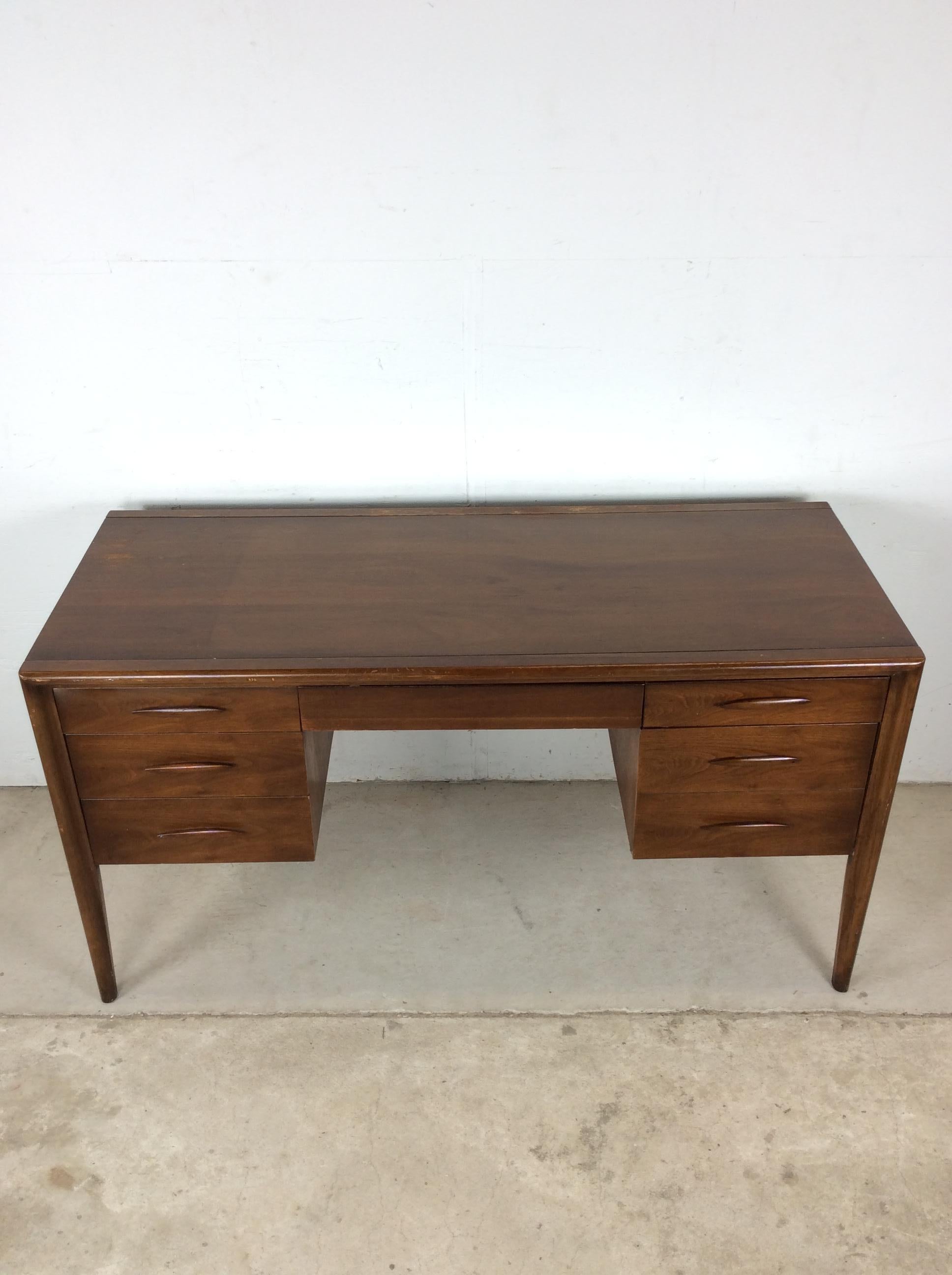 Questo scrittoio moderno di metà secolo di Broyhill presenta una struttura in legno massiccio, impiallacciatura in noce con finitura originale, sei cassetti a coda di rondine con tiretti in legno scolpito, paravento e schienale rifinito, in cima ad