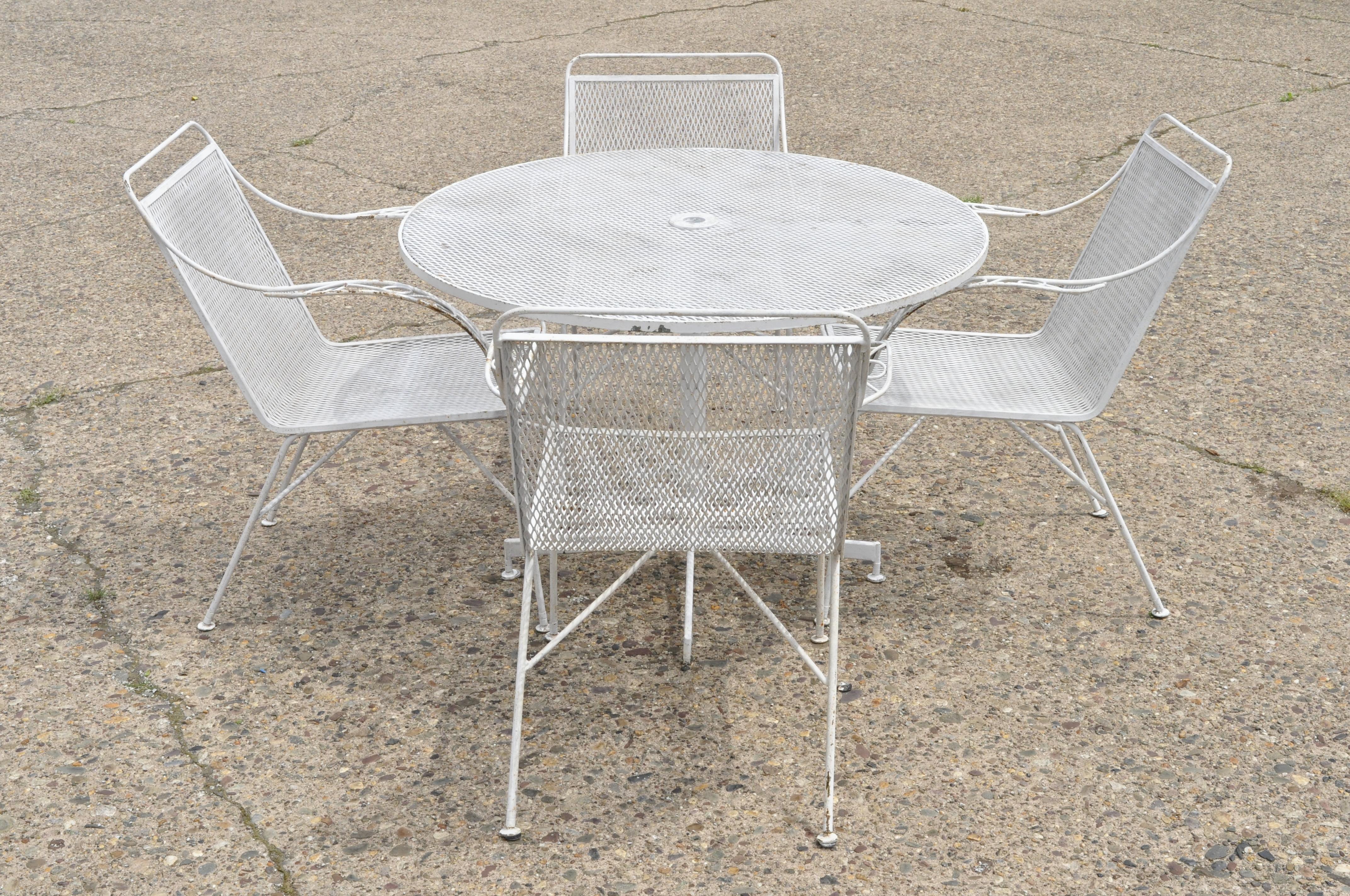 Mid-Century Modern wrought iron 5-piece patio garden dining set 4 chairs round table. Listing includes (4) chairs, (1) round table with pedestal base, unique stretcher base to chairs, wrought iron construction, clean modernist lines, quality