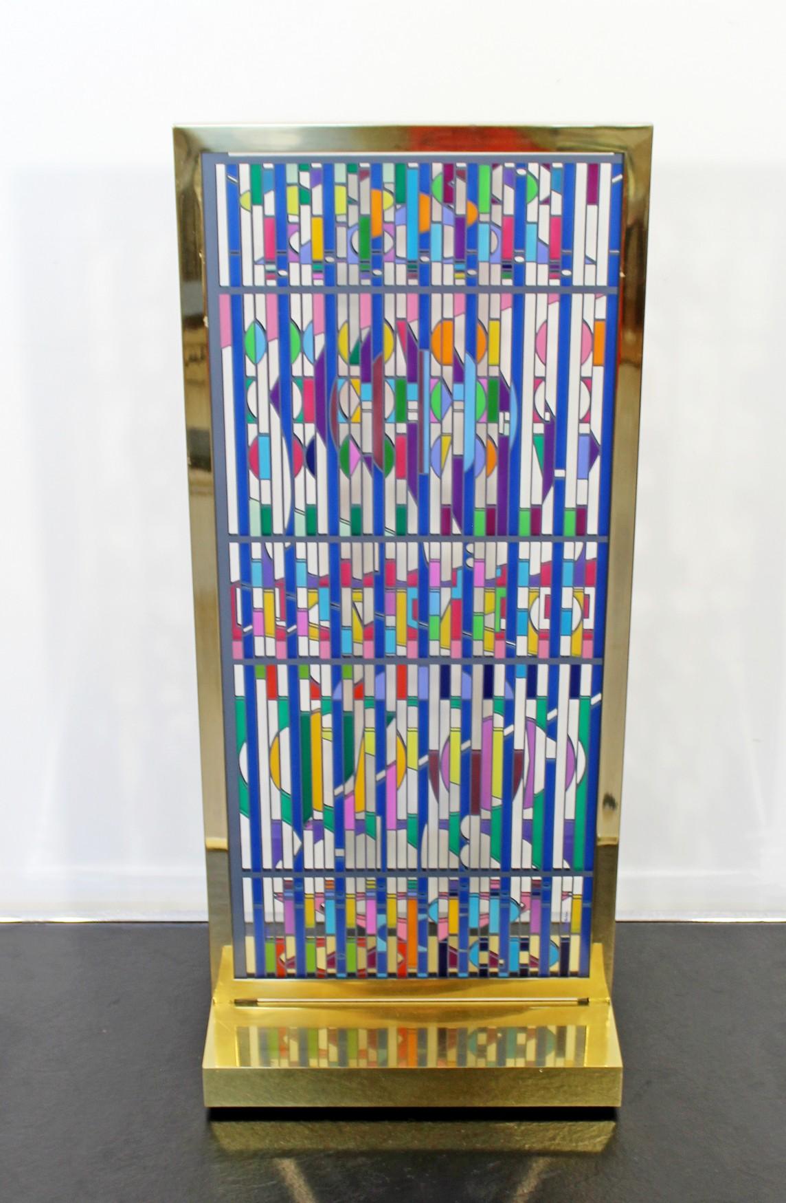 For your consideration is a silkscreen that was printed on movable plexi-glass, hand signed and numbered 81/99 by Yaacov Agam. It is hanging in a gilded brass frame and base Table sculpture. This piece measures 28