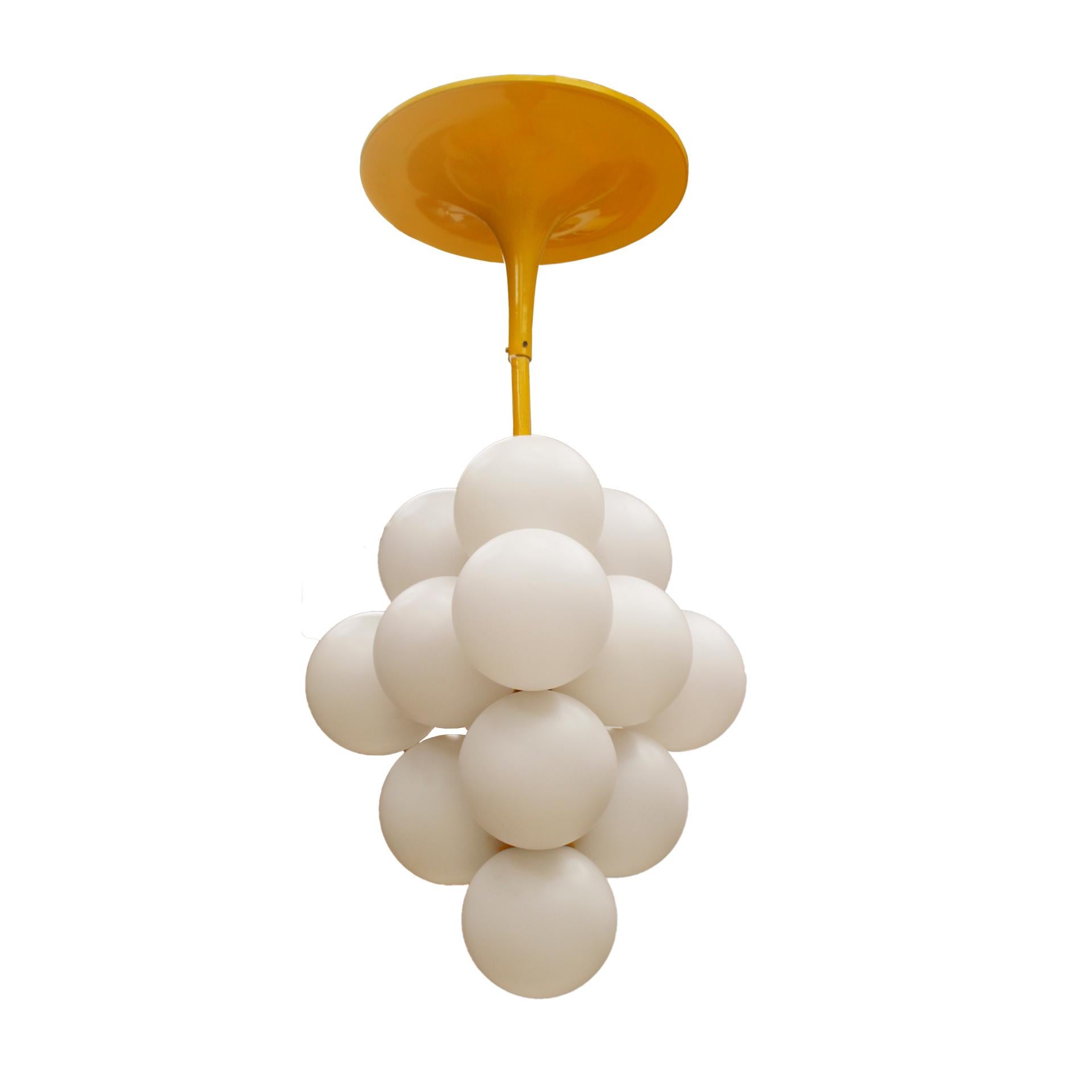 This Italian ceiling lamp from the 1970s is a stunning piece that exudes retro elegance. The centerpiece is a yellow lacquered metallic inverted trumpet-shaped rosette. Suspended from the rosette are several rounded opaline shades, carefully