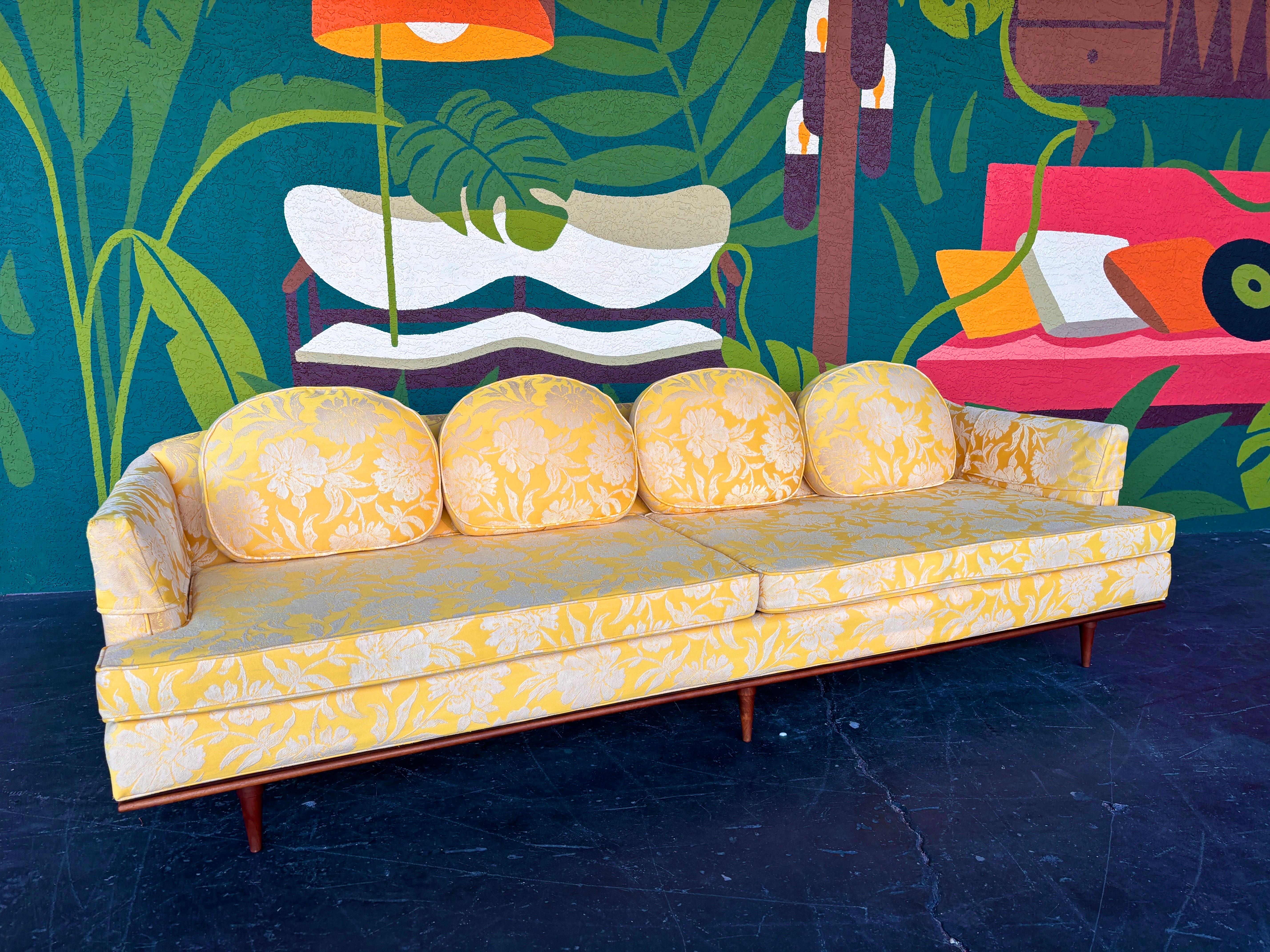 Mid Century Modern yellow and white floral brocade sofa with walnut accents c.1950’s. Overall good vintage condition. Semi Circular back cushions add an interesting twist. Some minor wear to removable arm rest covers and underside of one seat