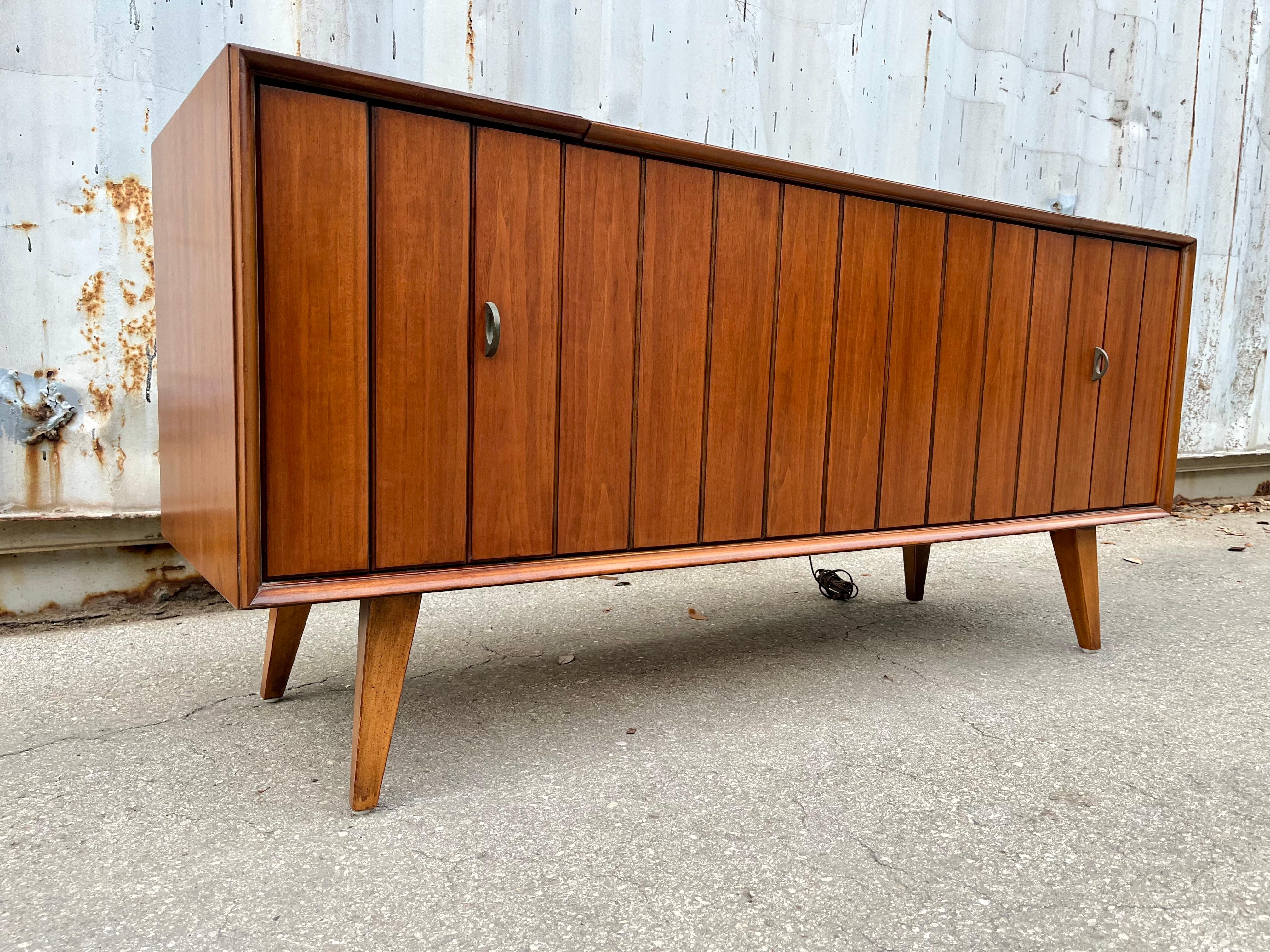 Fully refinished Mid Century Modern Zenith Record Player Stereo Console. Circa 1960s
Features a quintesential mid century modern design, a wonderfull walnut wood grain, louvered doors to conceal the speakers, and a compact size to fit in any small