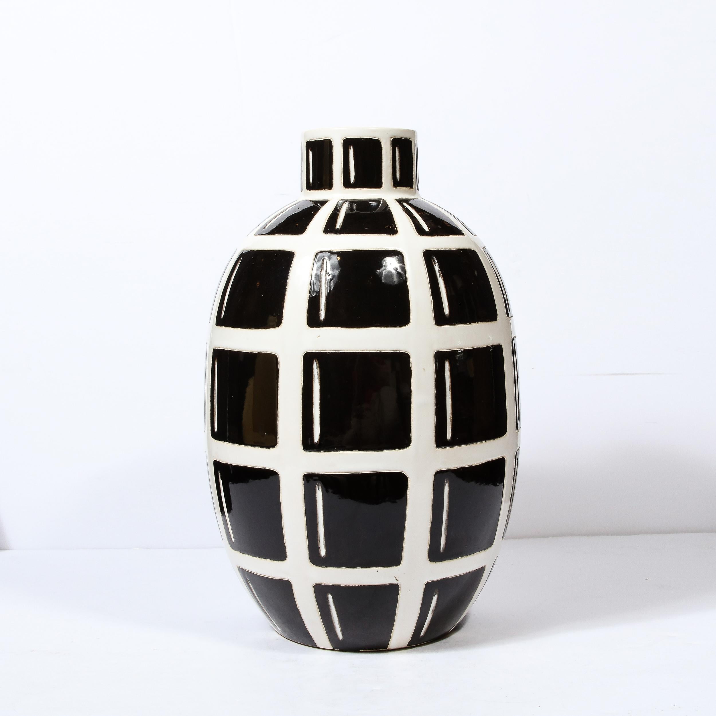 This bold and striking Mid-Century Modern ceramic vase was realized in the United States circa 1970. It features an elliptical black body with a grid form in white- offering a dramatic contrast- that resembles a stylized take on the hand grenade.